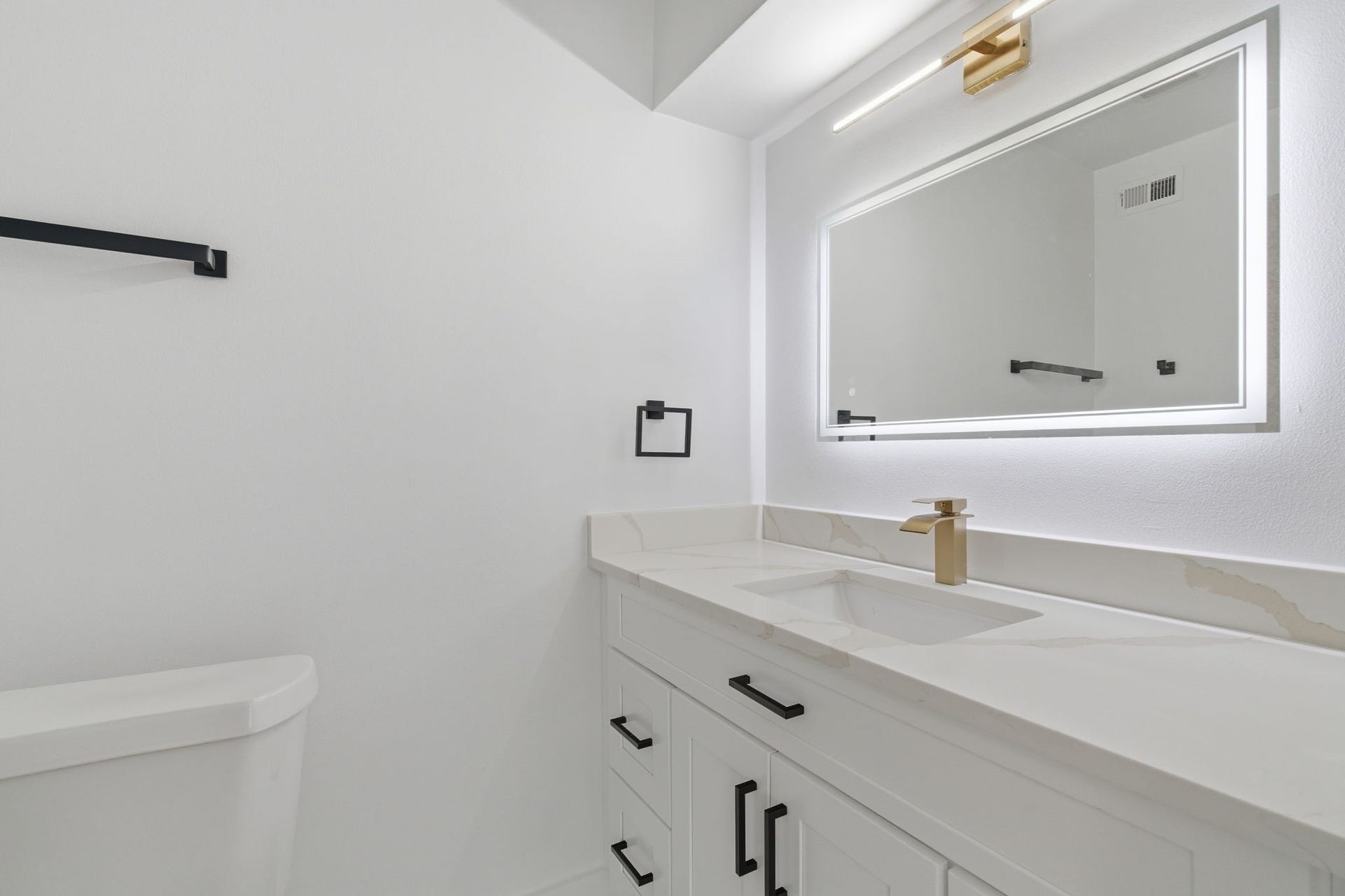 811 Lovett Boulevard, #21, Houston, TX 77006 The secondary bathroom carries the same updated style with an illuminated mirror, gold tone faucet, and black hardware.