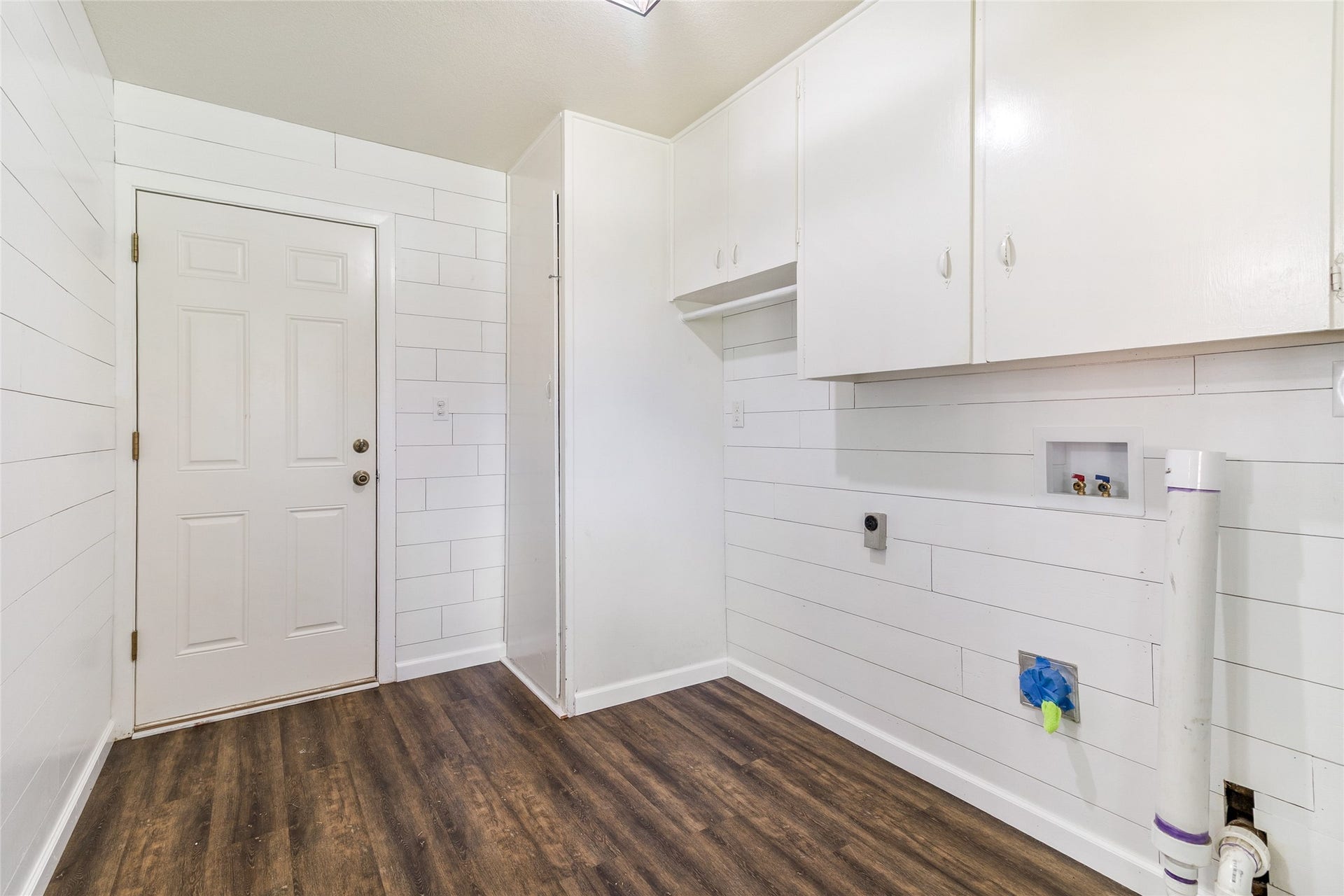 404 S 14th Street, West Columbia, TX 77486 Shiplap walls and updated lighting add character to the mudroom, while overhead cabinetry keeps laundry essentials organized.