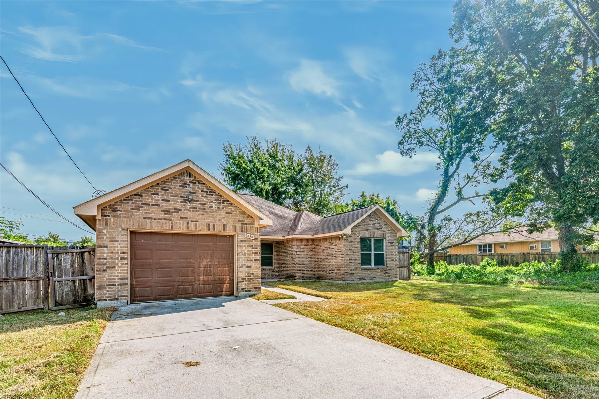 6528 Utah Street, Houston, TX 77091 Charming brick home with a spacious driveway, attached garage, and lush green yard, perfect for comfortable living.