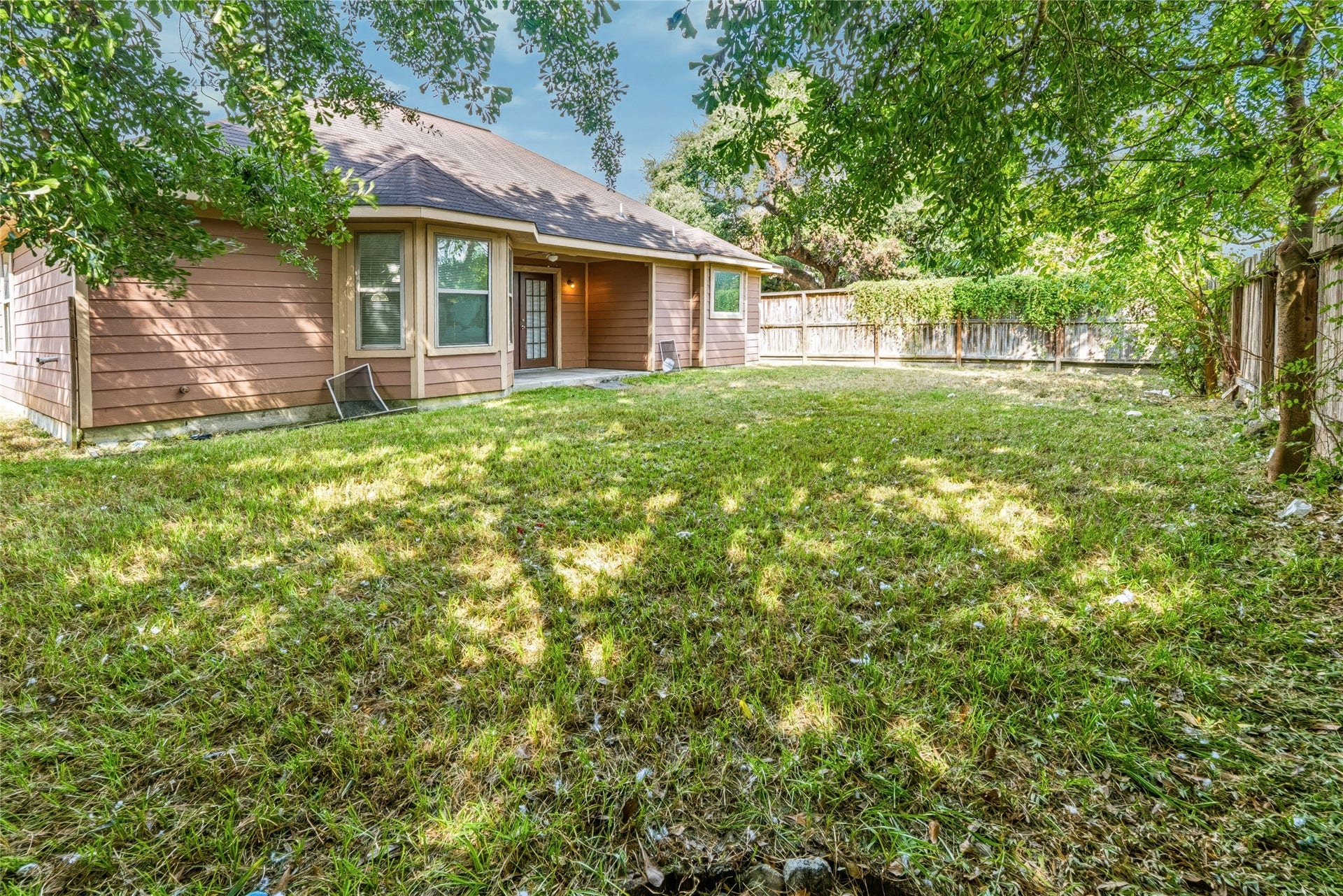6528 Utah Street, Houston, TX 77091 Charming backyard featuring a spacious lawn, mature trees, and a cozy covered patio perfect for outdoor relaxation and entertaining.