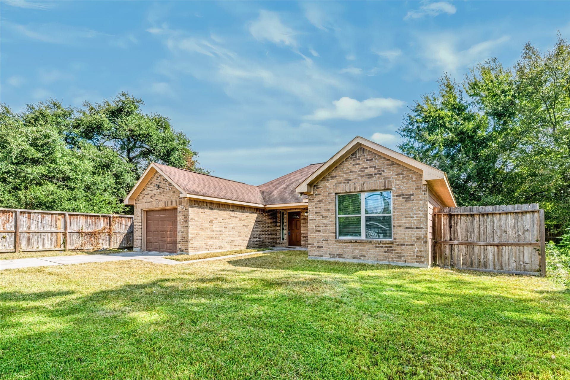 6528 Utah Street, Houston, TX 77091 Charming brick home with a spacious yard, inviting facade, and a single-car garage, nestled in a serene setting surrounded by mature trees.