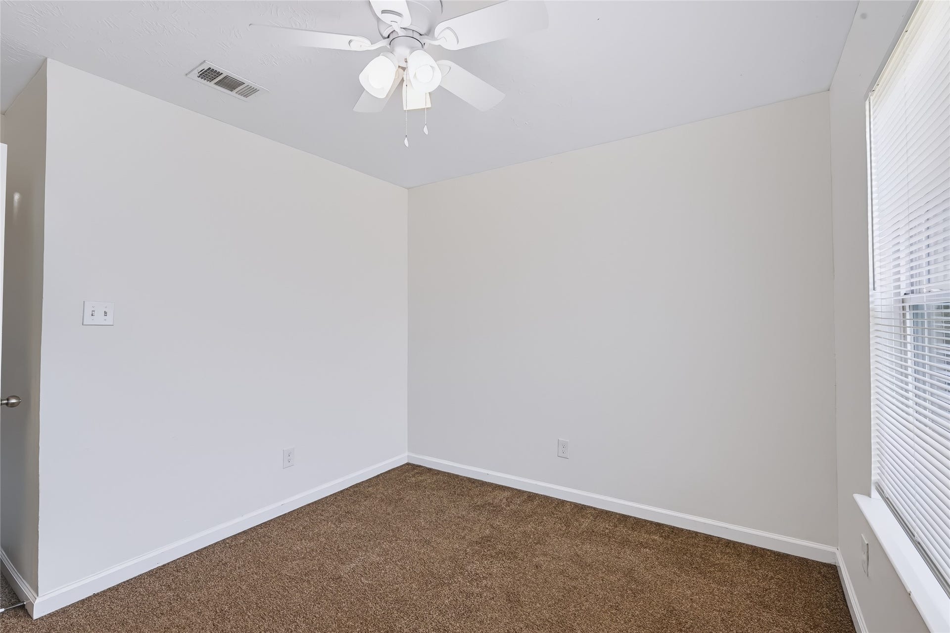 6528 Utah Street, Houston, TX 77091 Bright room with neutral walls, plush carpet, and ample natural light from a large window, perfect for a cozy bedroom or home office.