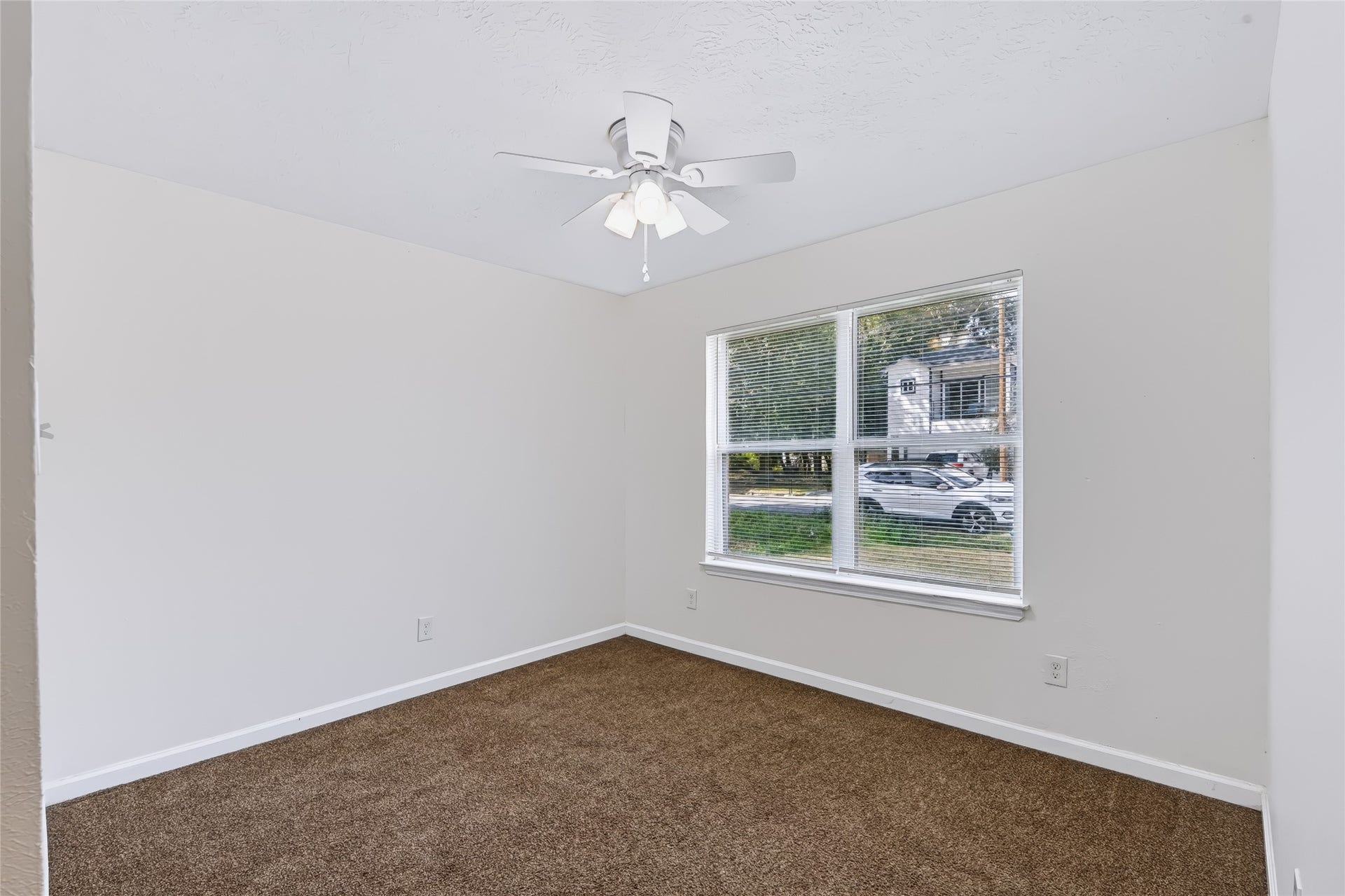 6528 Utah Street, Houston, TX 77091 Bright room with fresh white walls, plush brown carpeting, and a ceiling fan, complemented by a large window for natural light.