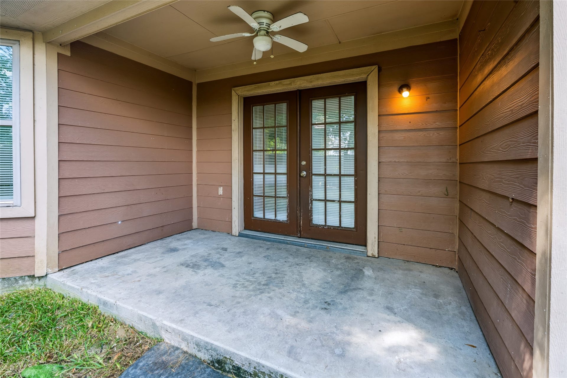 6528 Utah Street, Houston, TX 77091 Charming covered patio entrance with French doors and a cozy ceiling fan, perfect for relaxing outdoors.