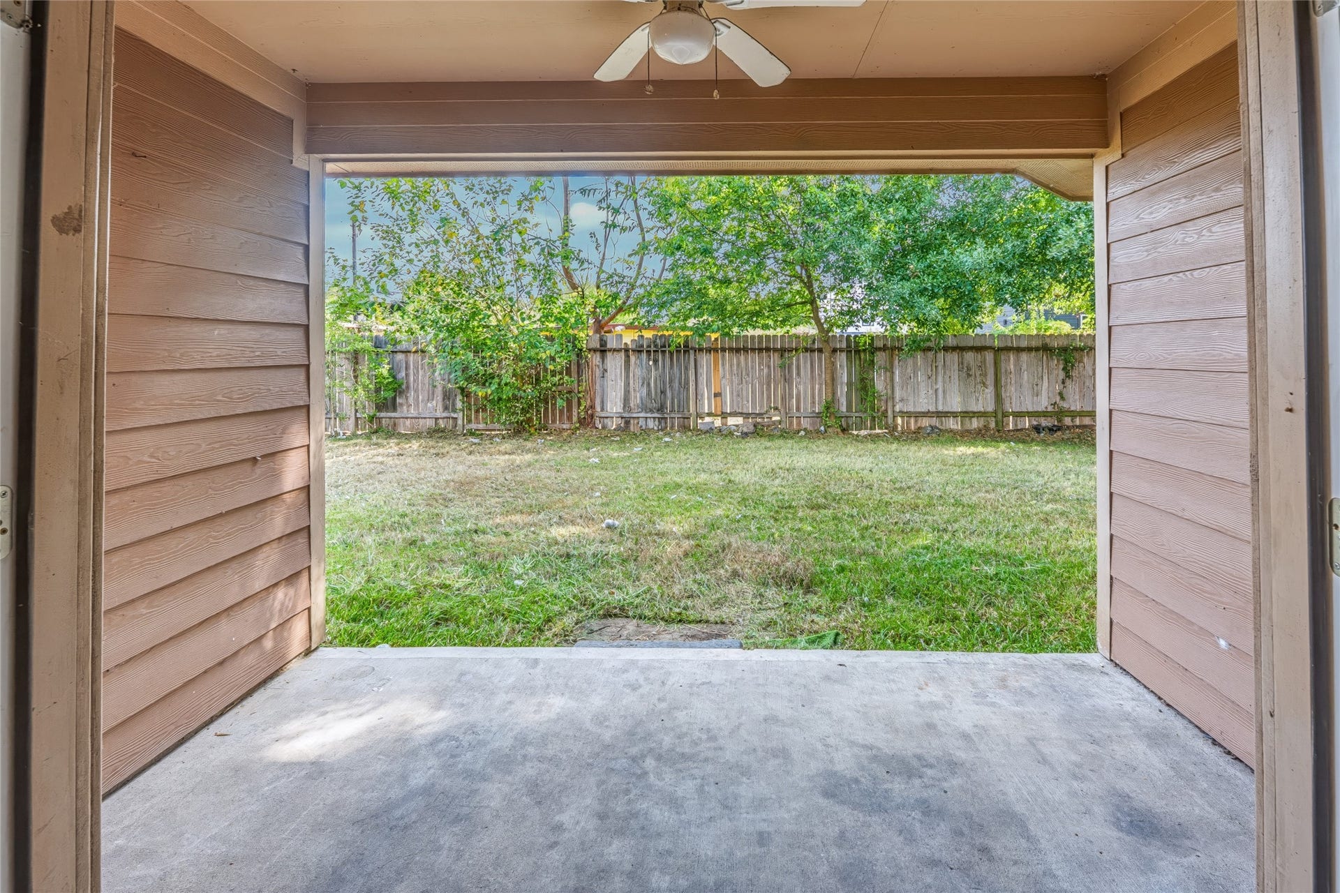 6528 Utah Street, Houston, TX 77091 Cozy covered patio with a ceiling fan overlooks a private, fenced backyard, perfect for relaxing or entertaining.