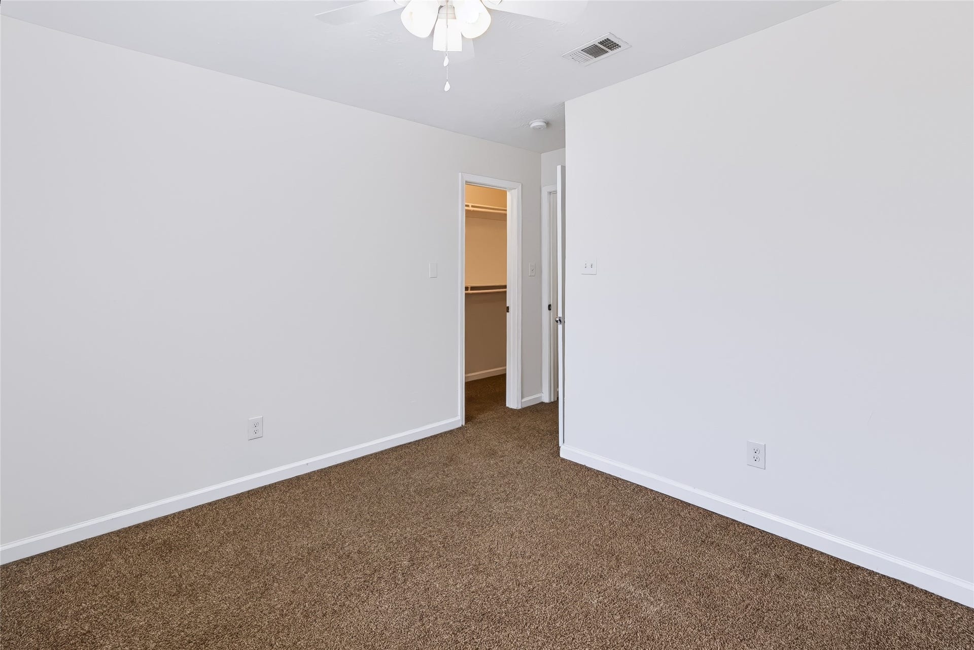 6528 Utah Street, Houston, TX 77091 Cozy bedroom with fresh carpeting, a ceiling fan, and ample natural light, leading to a convenient walk-in closet.
