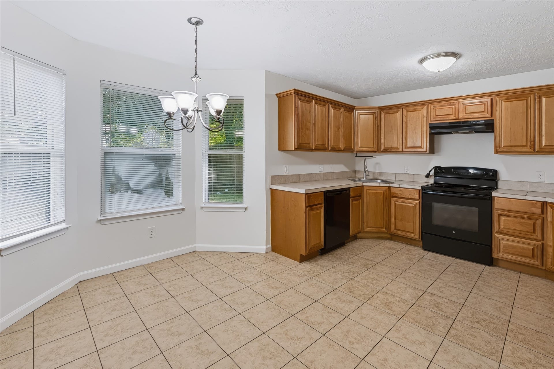 6528 Utah Street, Houston, TX 77091 Bright kitchen with ample wooden cabinetry, modern appliances, and a cozy dining area featuring large windows and a stylish chandelier.