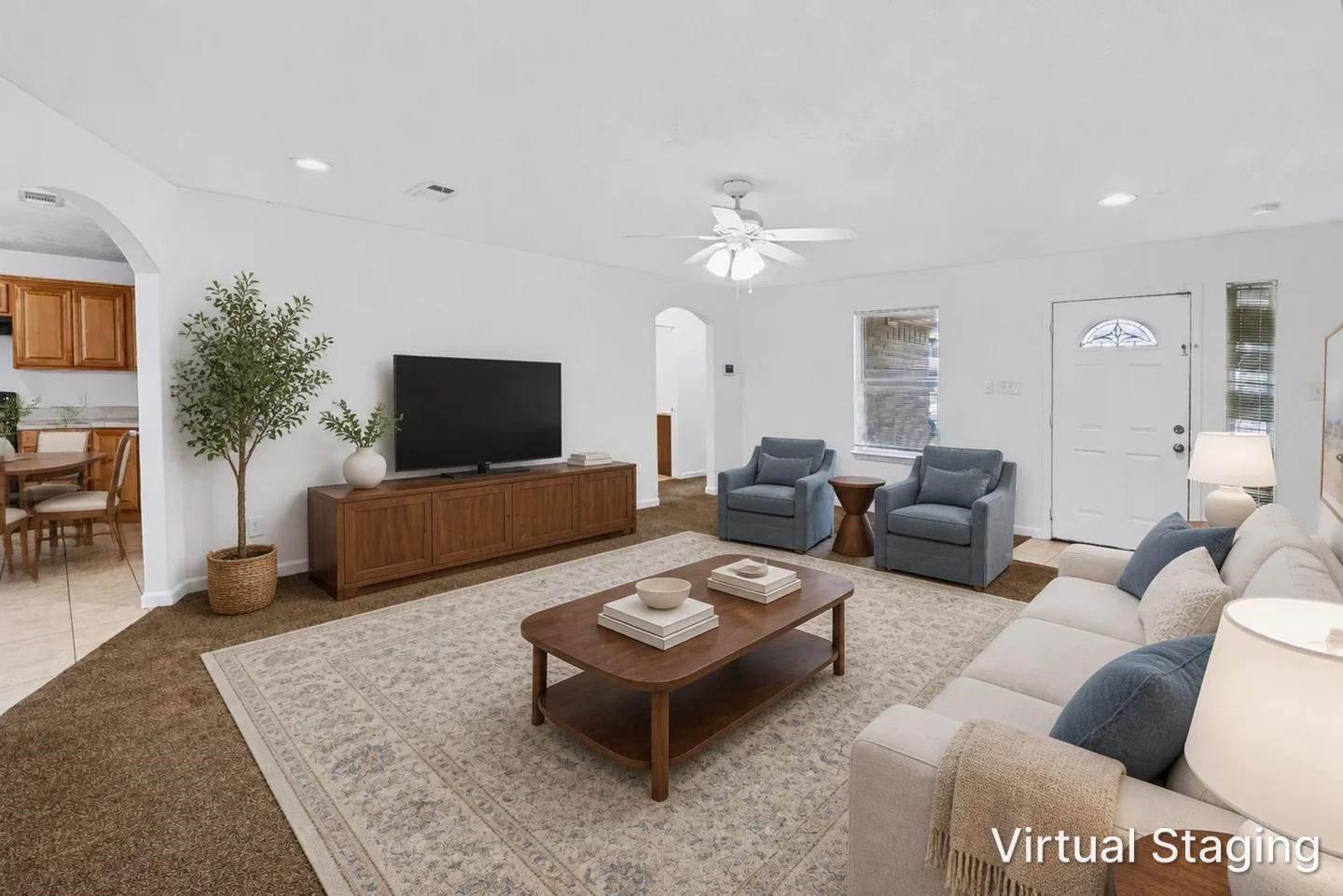 6528 Utah Street, Houston, TX 77091 Spacious living room with cozy seating, a ceiling fan, and abundant natural light, seamlessly connecting to the dining area through a charming archway.