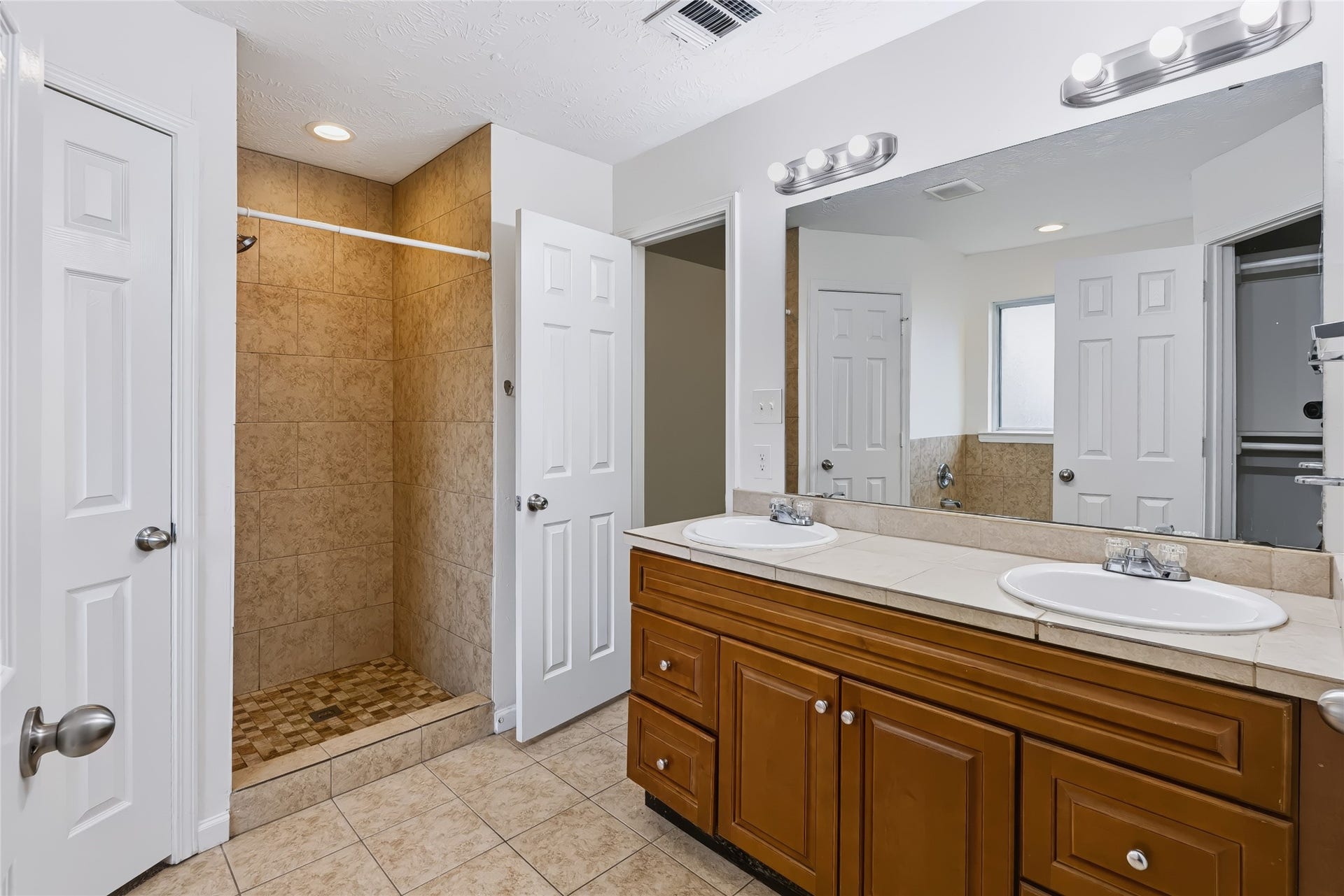 6528 Utah Street, Houston, TX 77091 Spacious bathroom featuring a double vanity with ample storage and a walk-in shower, accented by neutral tile and modern lighting.