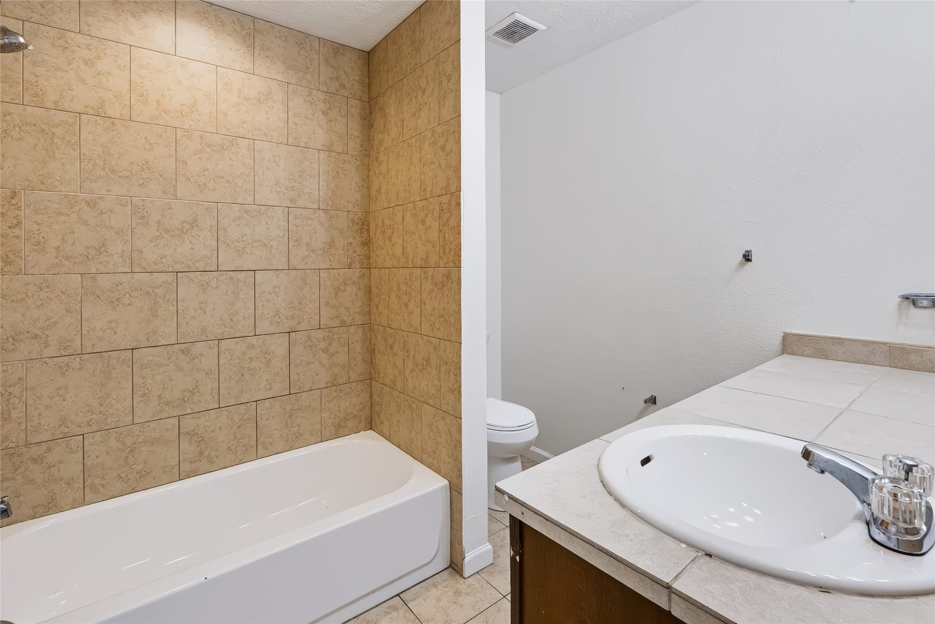 6528 Utah Street, Houston, TX 77091 Modern bathroom featuring a tiled shower and bathtub combination, sleek vanity with ample counter space, and a neutral color palette.