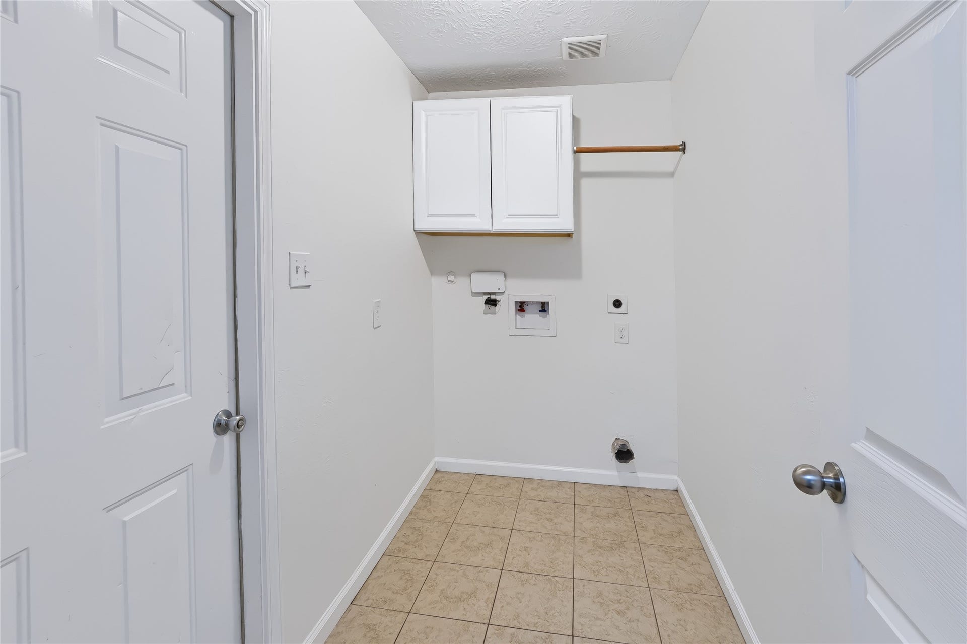 6528 Utah Street, Houston, TX 77091 Spacious laundry room with tile flooring, equipped with hookups for washer and dryer, and featuring an overhead cabinet for storage.