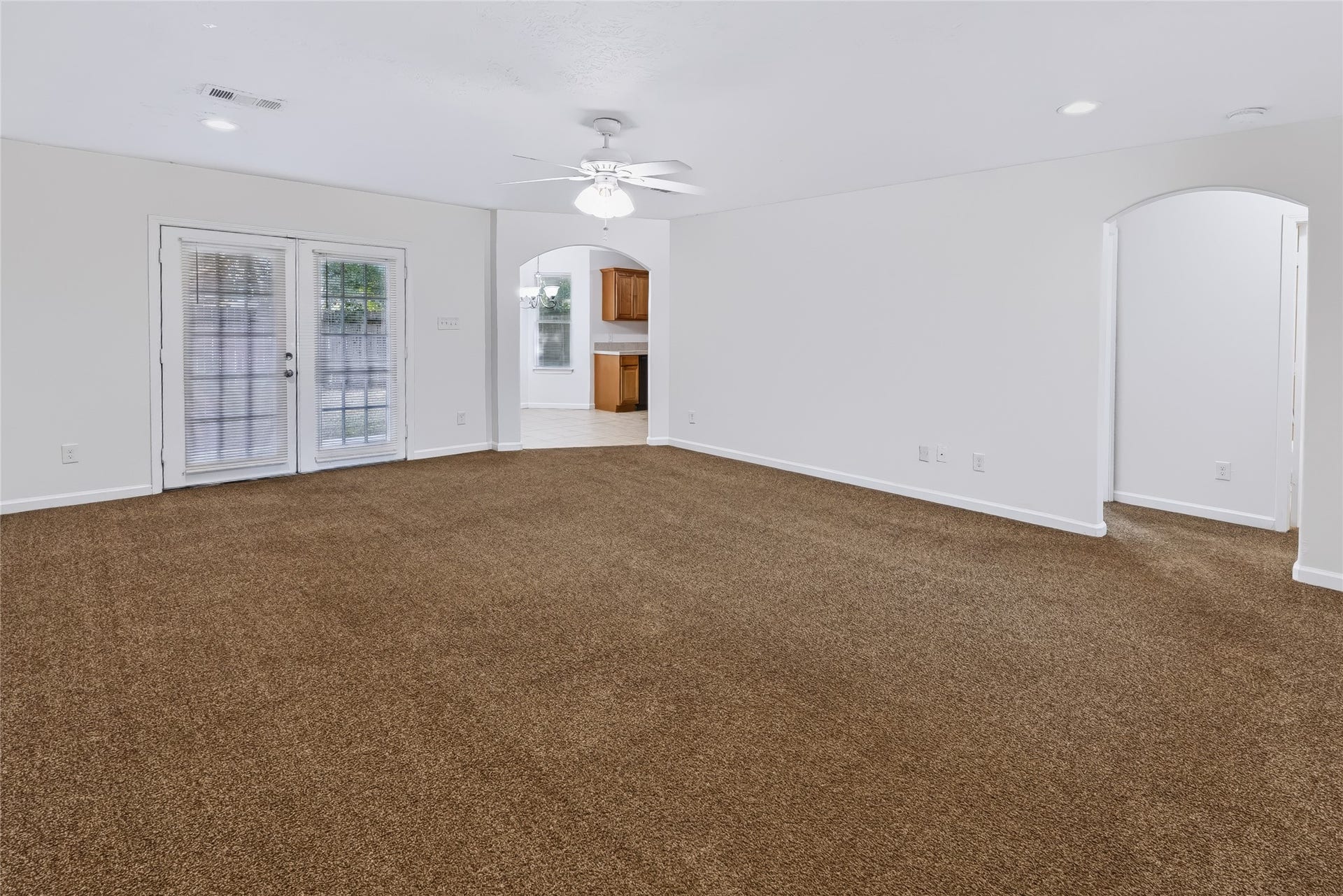 6528 Utah Street, Houston, TX 77091 Spacious living area with plush carpeting, neutral walls, and French doors leading to an outdoor space.