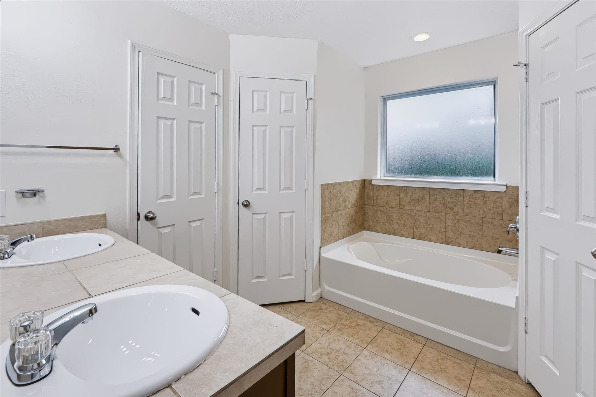 6528 Utah Street, Houston, TX 77091 Spacious bathroom featuring a dual-sink vanity and a relaxing bathtub with tile surround, complemented by a privacy window for natural light.