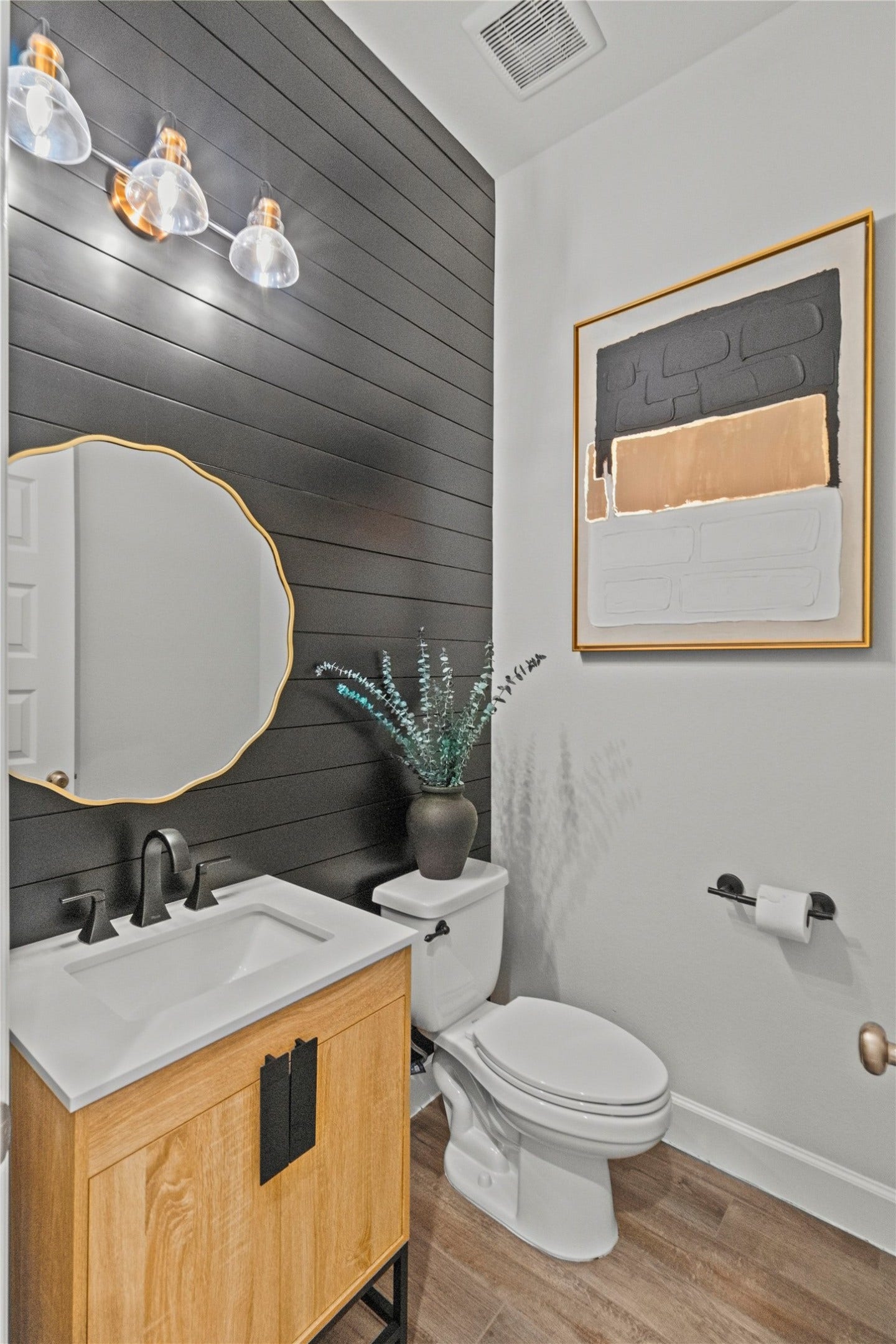 9934 Starry Night Lane, Manvel, TX 77578 Chic powder room with a modern black shiplap accent wall, sleek fixtures, and stylish artwork, offering a blend of contemporary and rustic charm.