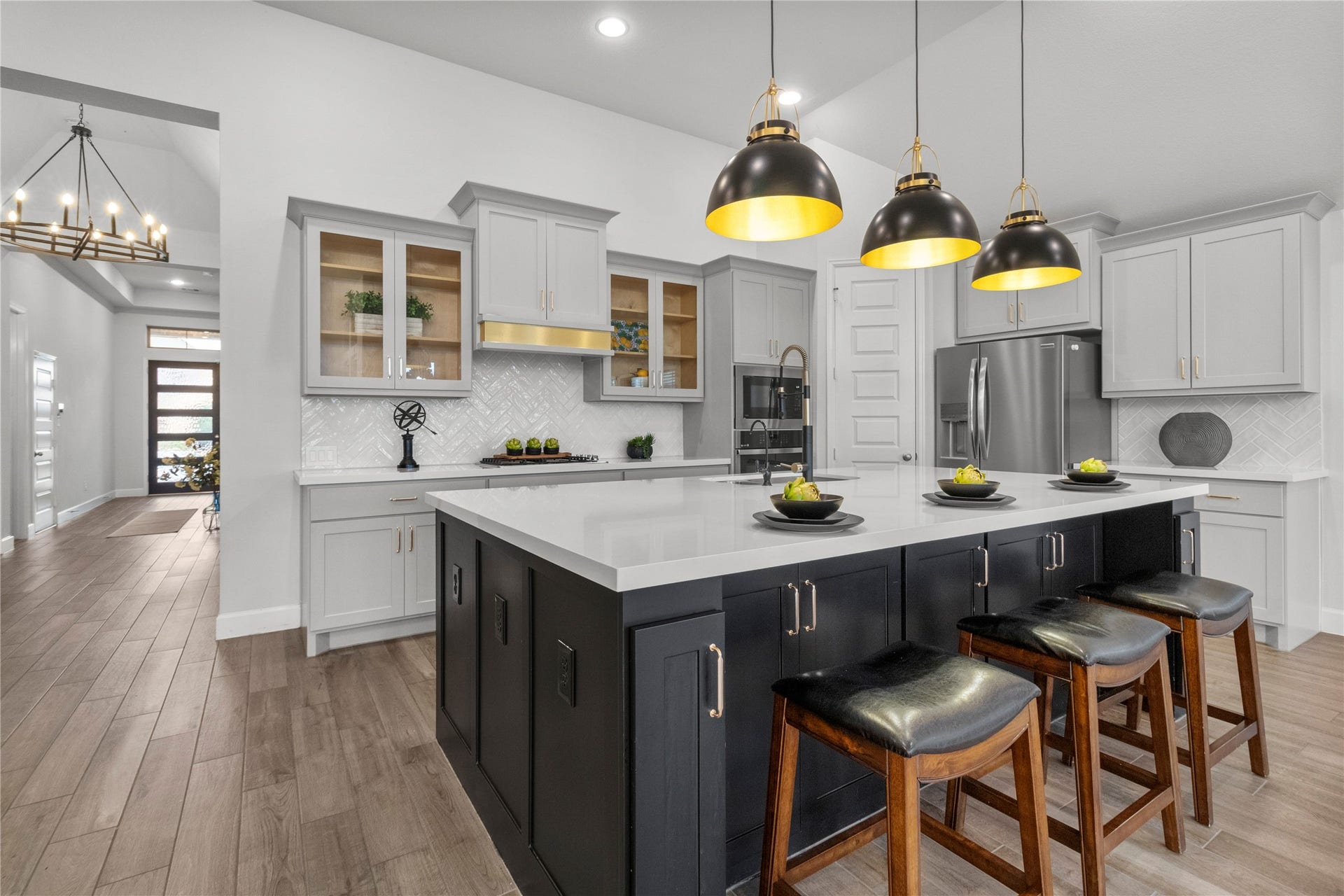 9934 Starry Night Lane, Manvel, TX 77578 Stunning modern kitchen featuring a spacious island with sleek black cabinetry, elegant pendant lighting, and stainless steel appliances.