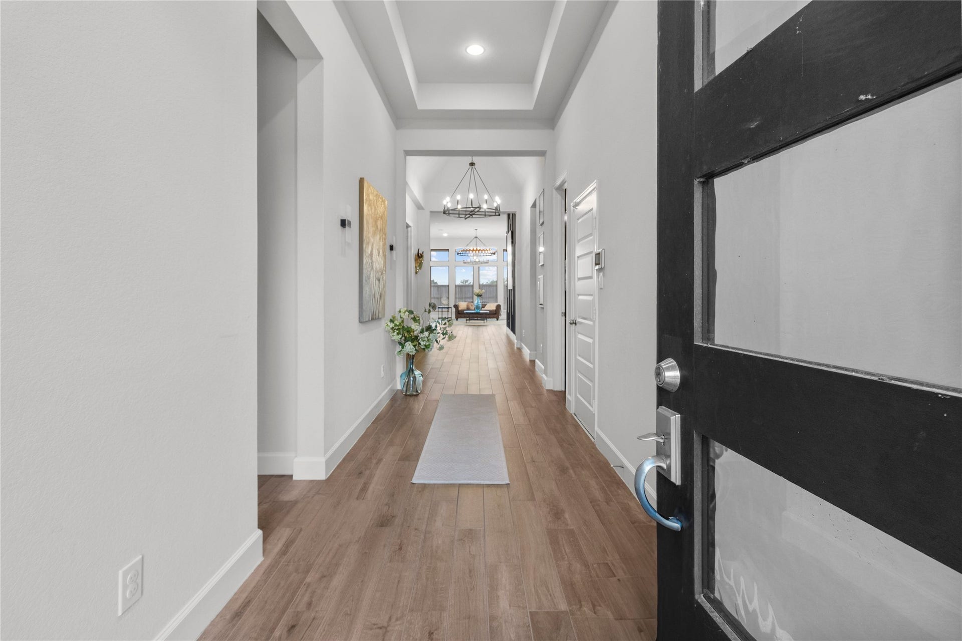 9934 Starry Night Lane, Manvel, TX 77578 Step into a welcoming foyer with elegant hardwood flooring and a modern chandelier, leading to a bright, open living space.