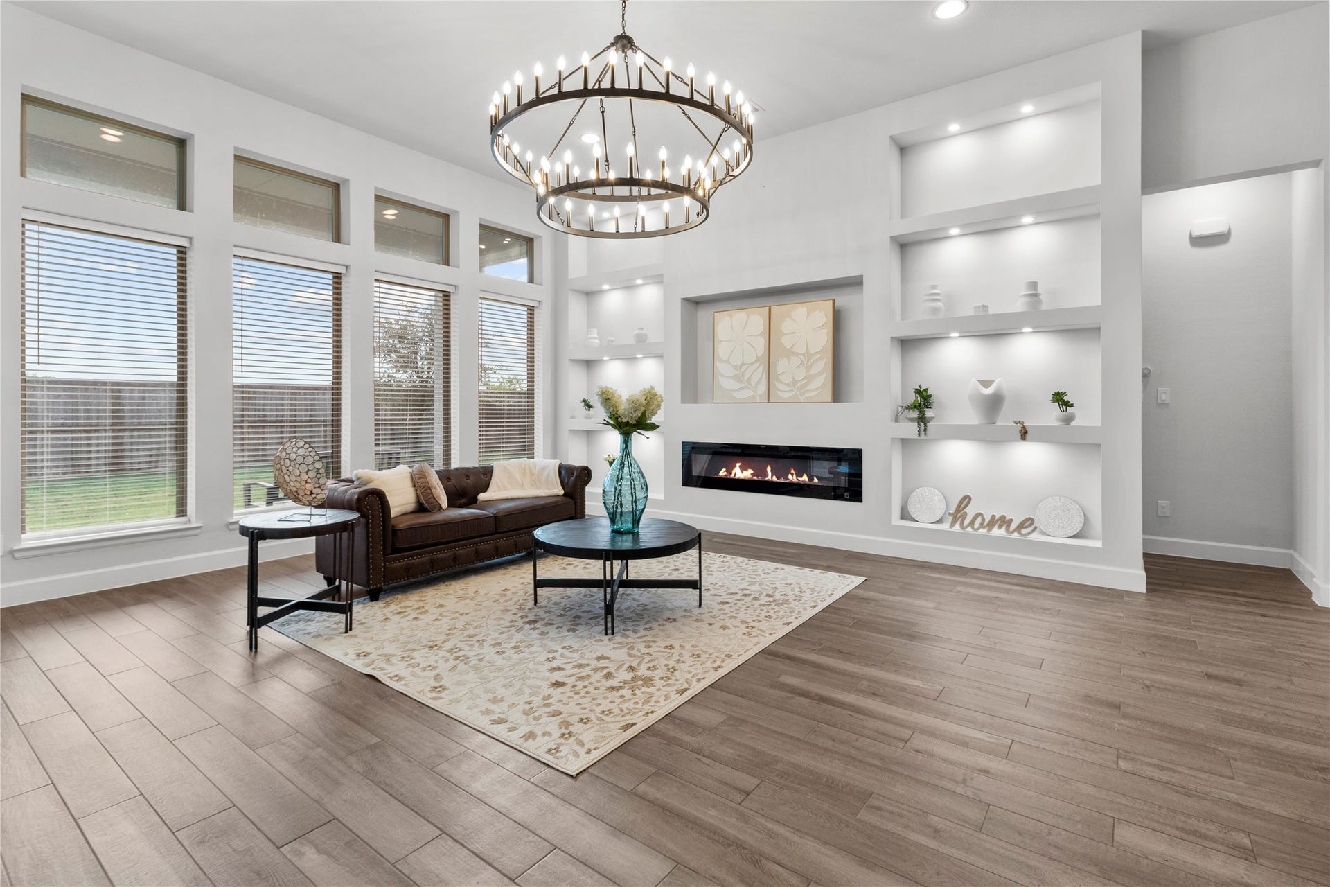 9934 Starry Night Lane, Manvel, TX 77578 Elegant living room with a modern fireplace, built-in shelving, and large windows offering plenty of natural light.