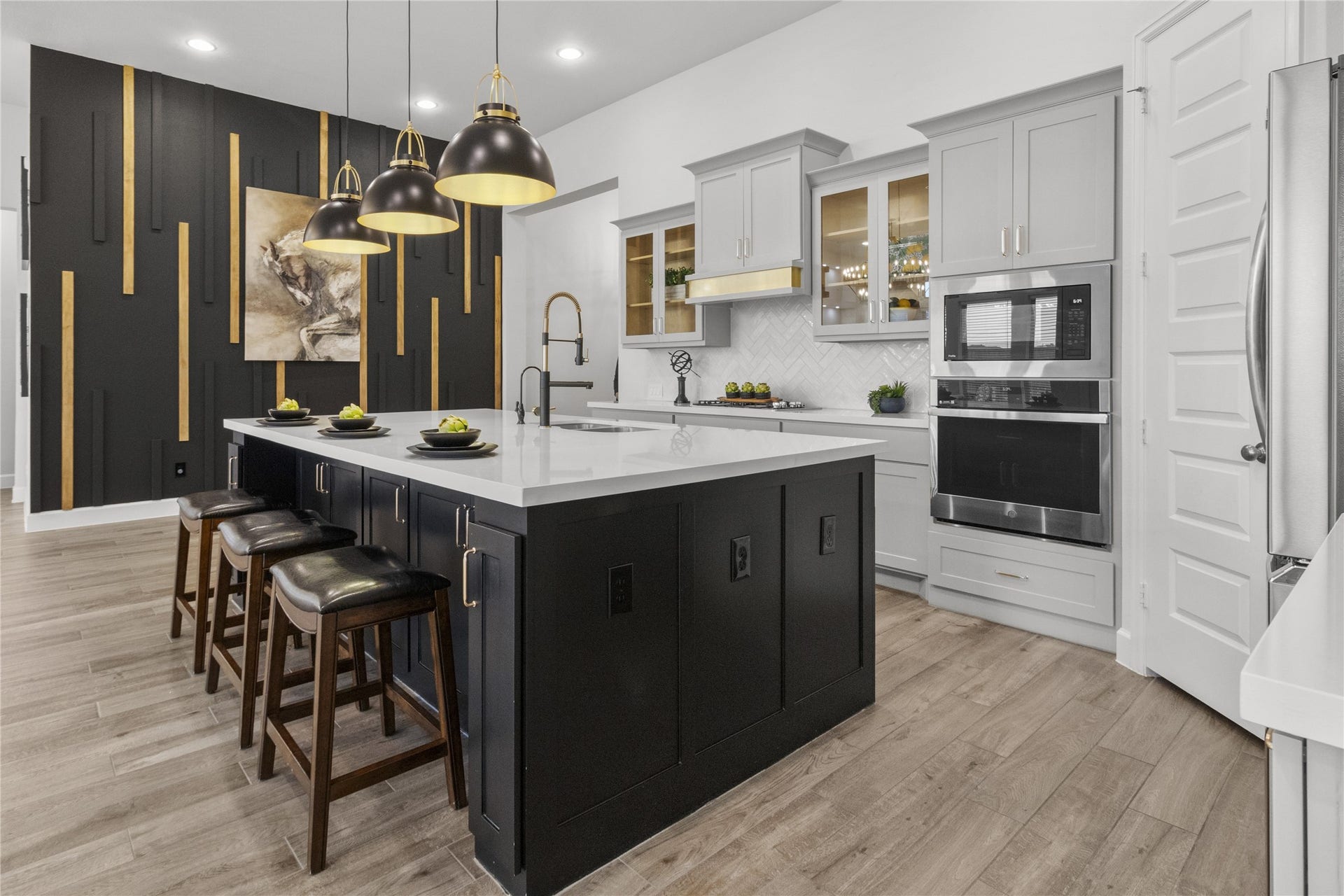 9934 Starry Night Lane, Manvel, TX 77578 Sleek and modern kitchen with a large island, pendant lighting, and stylish black and gold accents. The open layout features white cabinetry, stainless steel appliances, and a sophisticated backsplash.