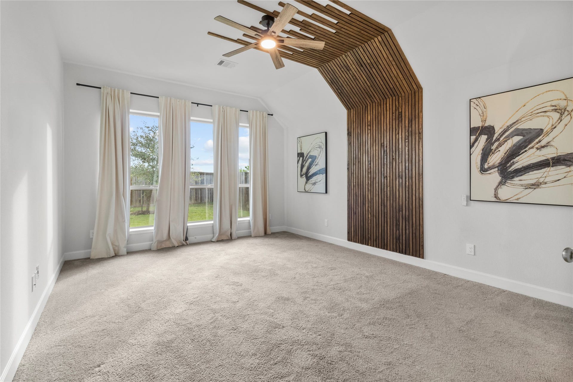 9934 Starry Night Lane, Manvel, TX 77578 Spacious room with large windows offering abundant natural light, featuring a unique wood accent wall and modern ceiling fan, perfect for a stylish retreat. Primary Bedroom