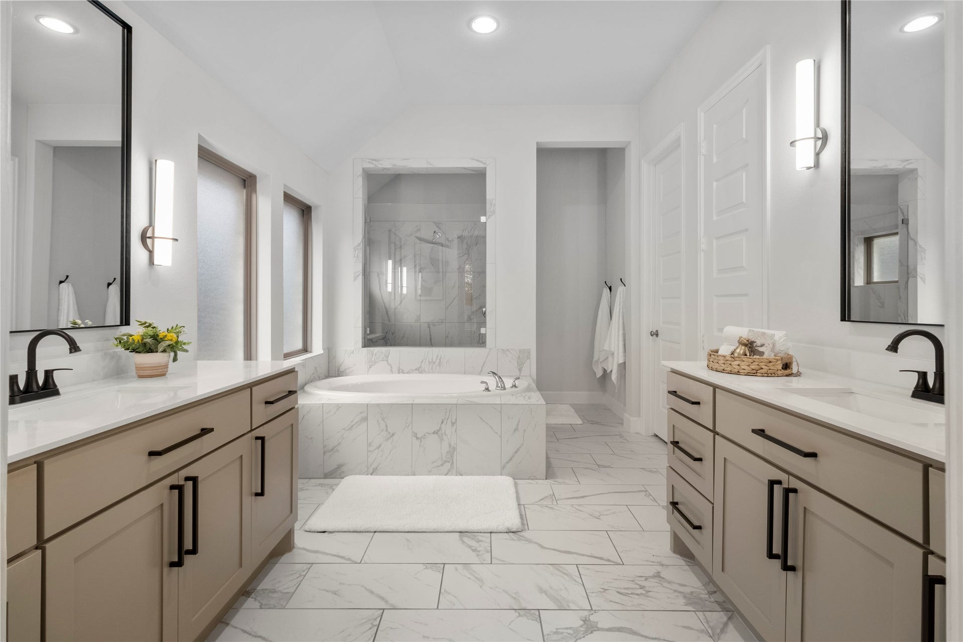 9934 Starry Night Lane, Manvel, TX 77578 Luxurious bathroom featuring a spacious soaking tub, dual vanities with elegant fixtures, and modern lighting, all complemented by sleek tile flooring.