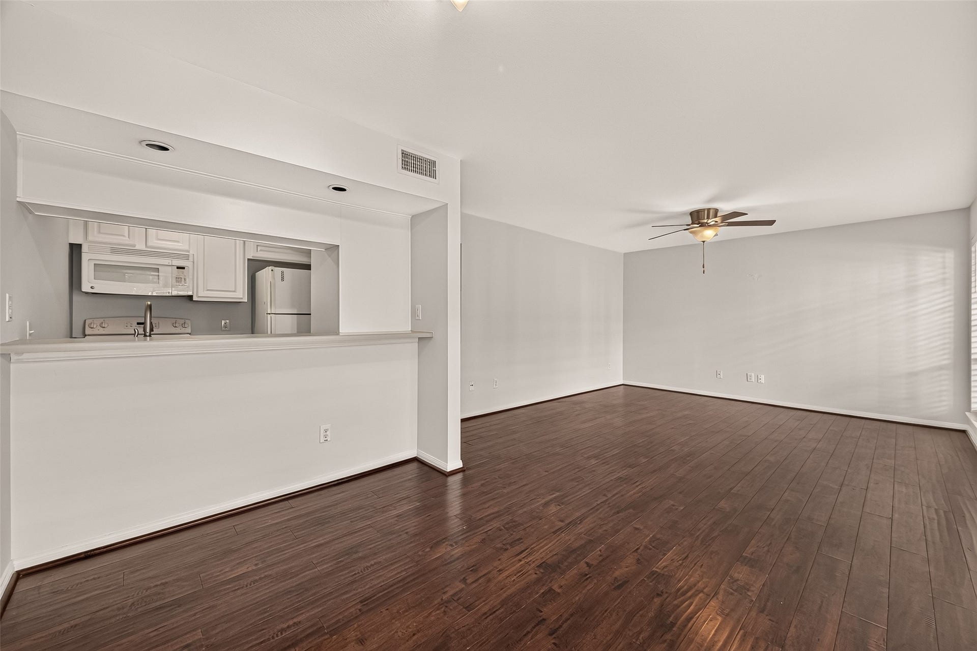 5343 Richmond Avenue, #4, Houston, TX 77056 Spacious open-concept living area with elegant hardwood floors, a sleek ceiling fan, and a cozy kitchen pass-through for easy entertaining.
