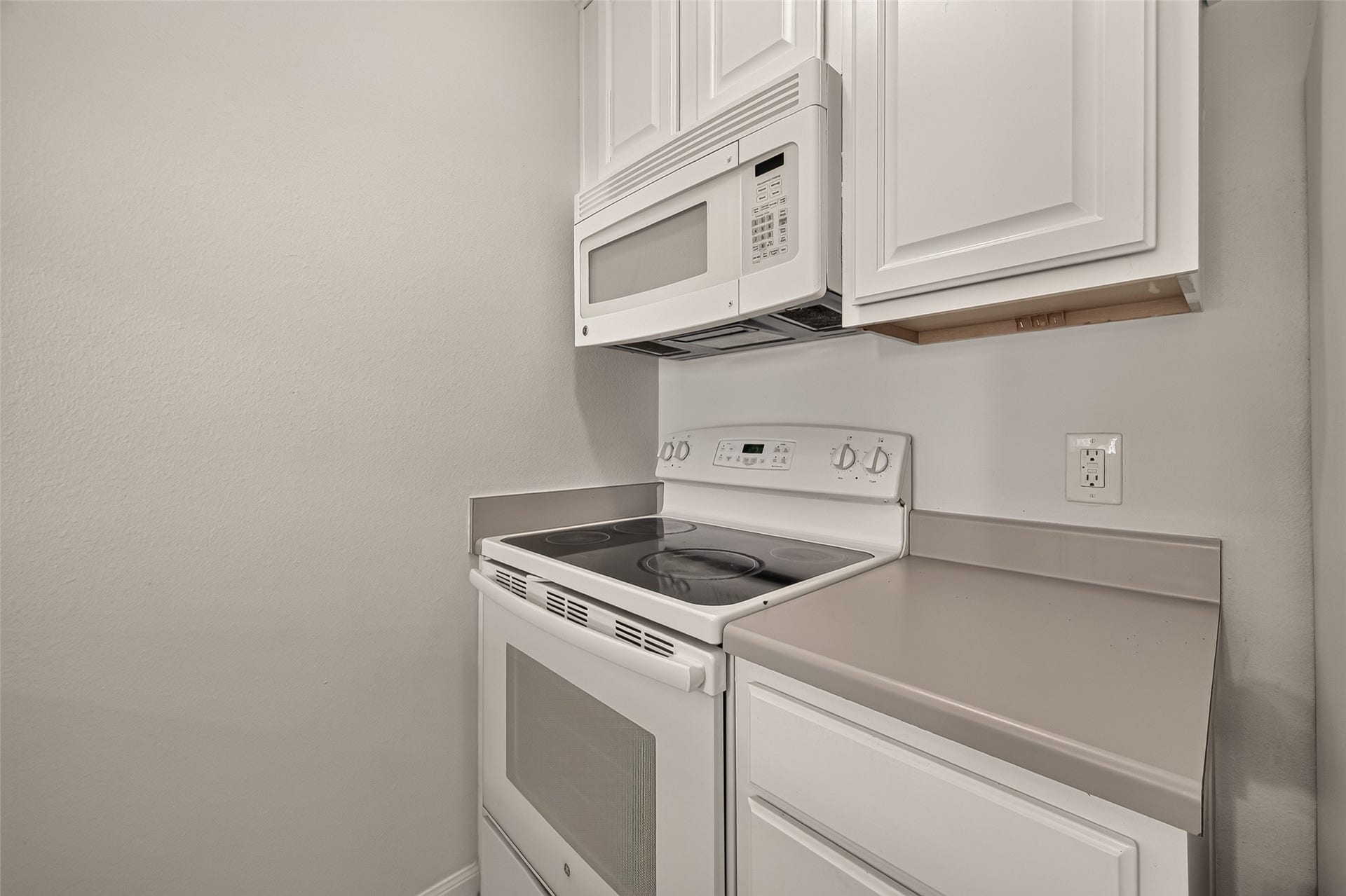 5343 Richmond Avenue, #4, Houston, TX 77056 Modern kitchen corner featuring sleek white cabinetry, an electric stove, and a built-in microwave for convenience.