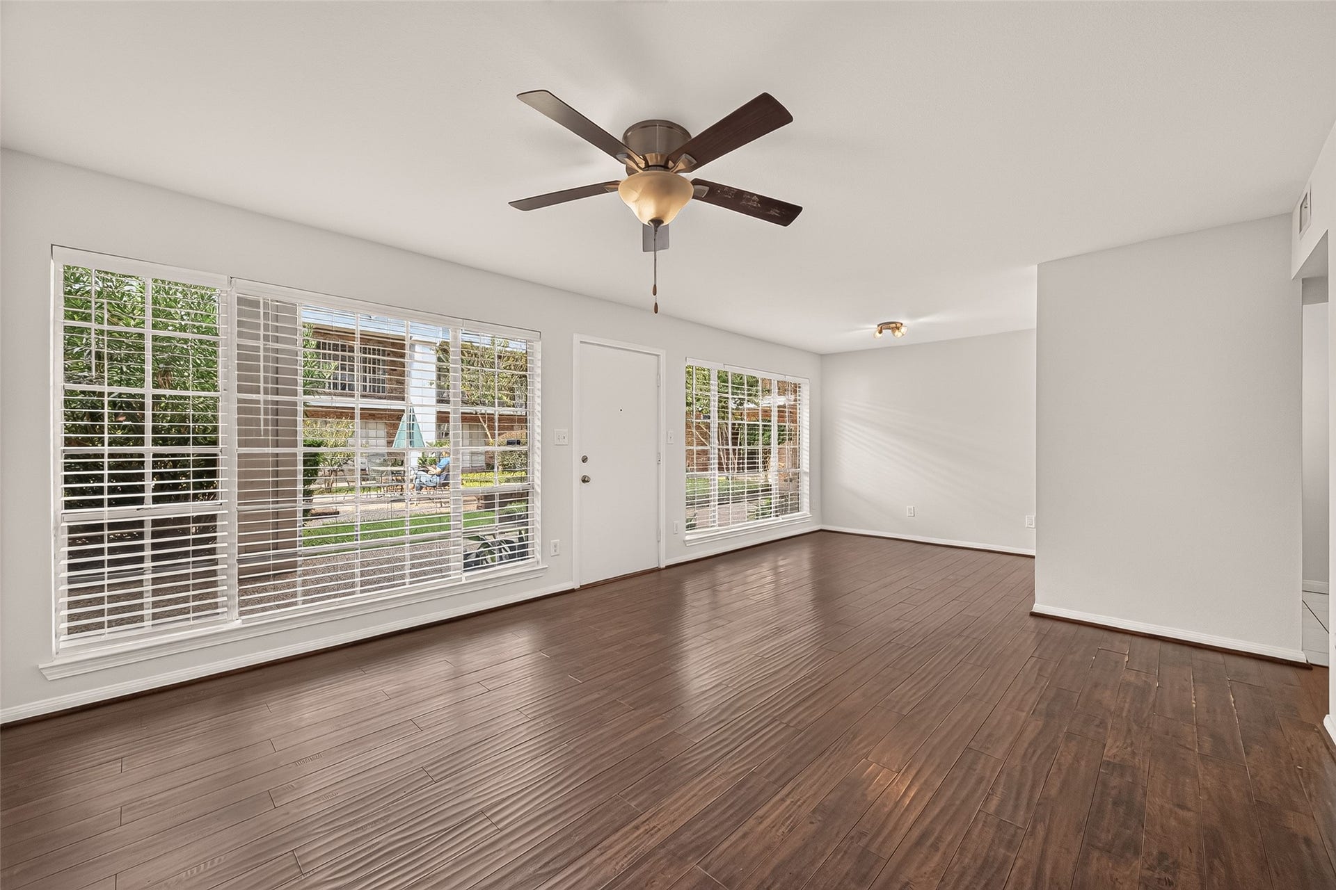 5343 Richmond Avenue, #4, Houston, TX 77056 Spacious living area with rich hardwood floors, abundant natural light from large windows, and a modern ceiling fan, offering a warm and inviting atmosphere.