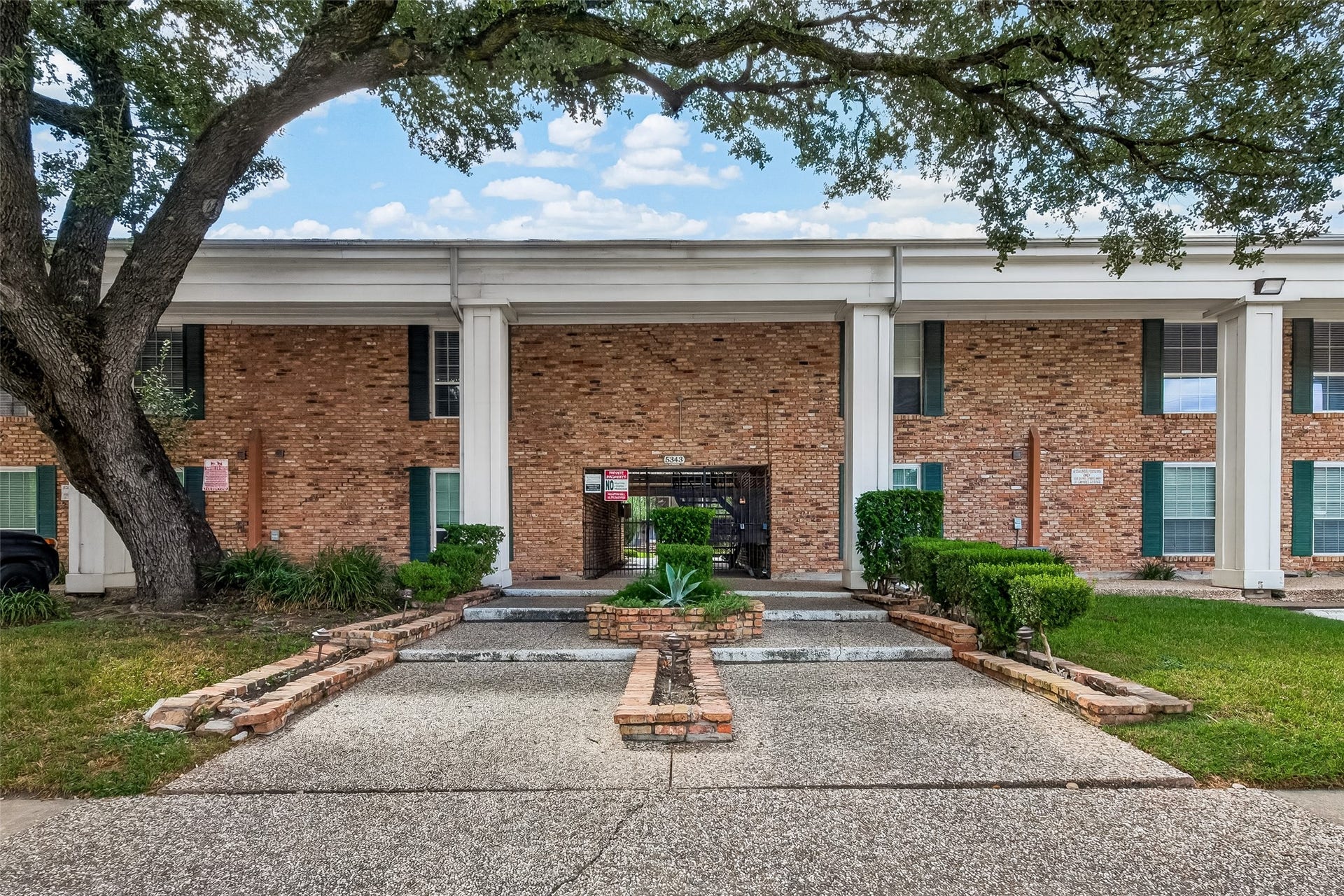 5343 Richmond Avenue, #4, Houston, TX 77056 Charming brick townhouse with classic columns and lush landscaping, offering a welcoming entrance and a blend of traditional and modern appeal.