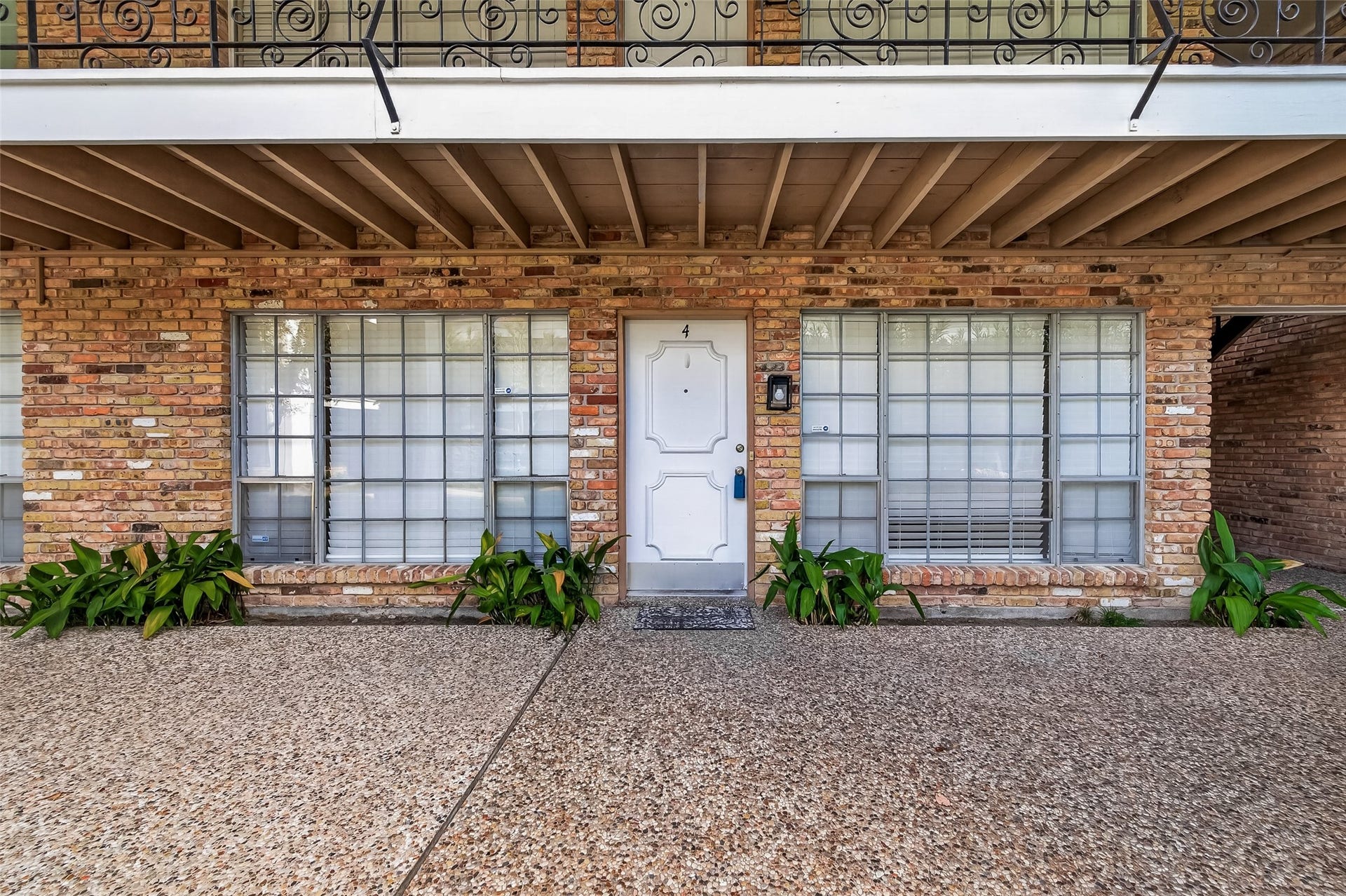 5343 Richmond Avenue, #4, Houston, TX 77056 Charming brick exterior with large windows and a welcoming front door, complemented by elegant ironwork and lush greenery.