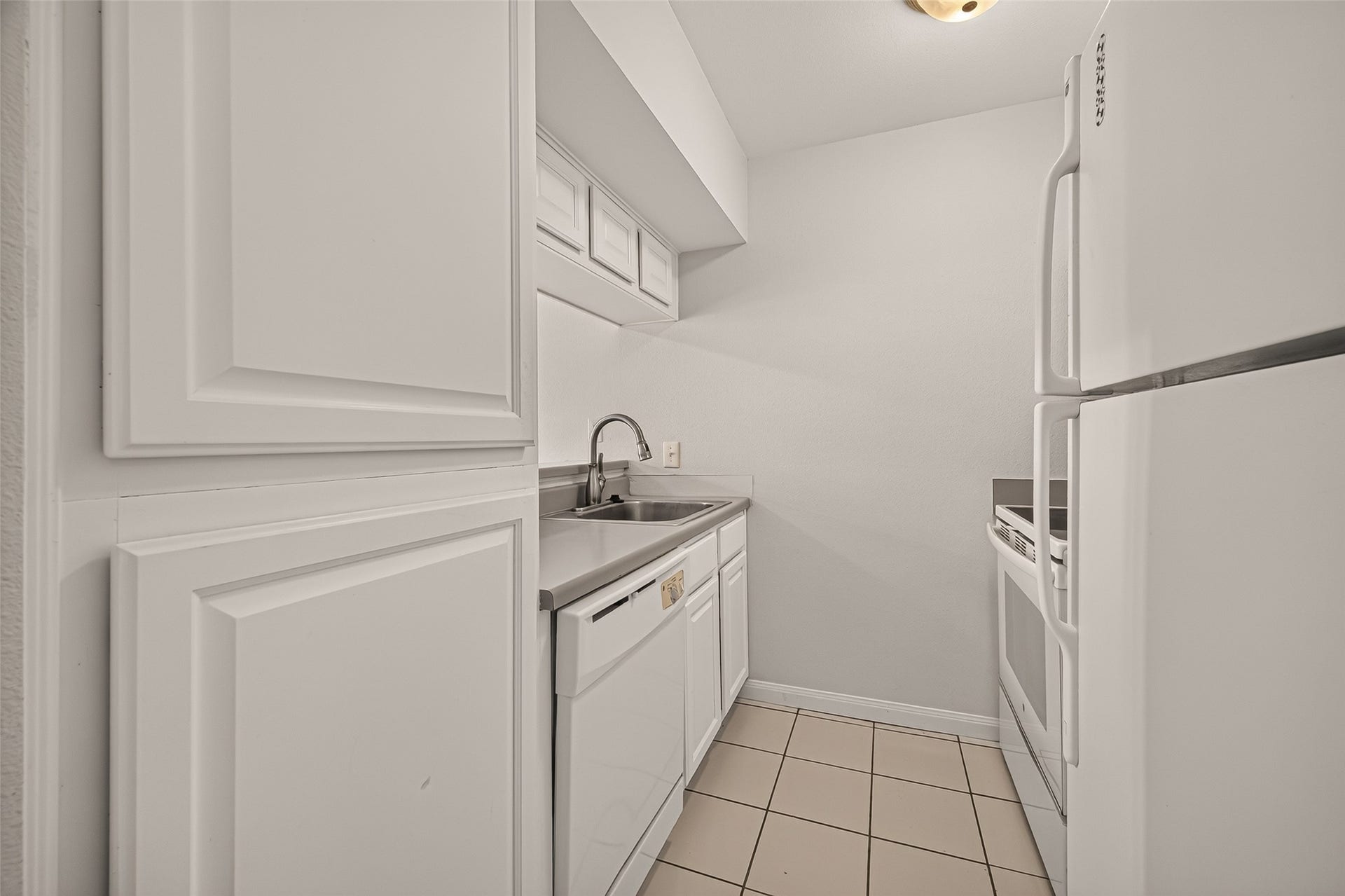 5343 Richmond Avenue, #4, Houston, TX 77056 Charming galley kitchen with sleek white cabinets, tile flooring, and modern appliances, offering a clean and functional space.