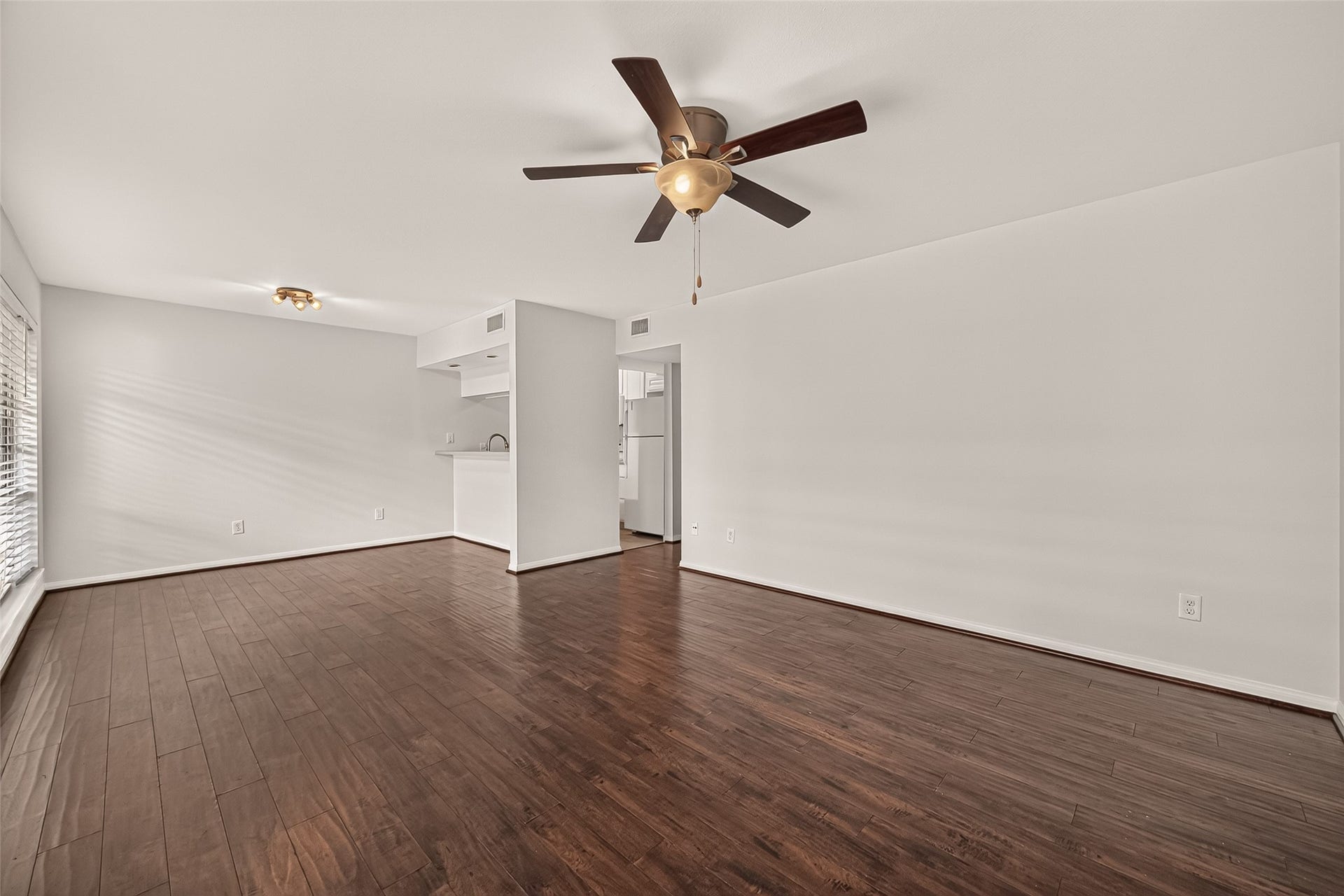 5343 Richmond Avenue, #4, Houston, TX 77056 Spacious living area with elegant dark wood flooring and a ceiling fan, seamlessly flowing into a cozy kitchen nook.