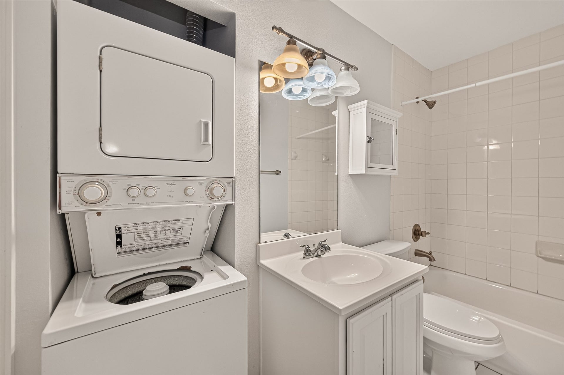 5343 Richmond Avenue, #4, Houston, TX 77056 Compact bathroom with a convenient in-unit stacked washer and dryer, modern lighting, and a pristine tiled bathtub.