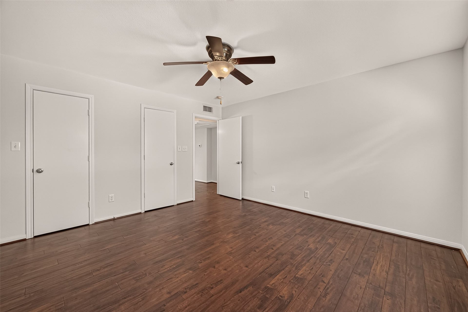 5343 Richmond Avenue, #4, Houston, TX 77056 Spacious room featuring elegant hardwood flooring and a modern ceiling fan, complemented by neutral wall tones and multiple doorways for versatile use.