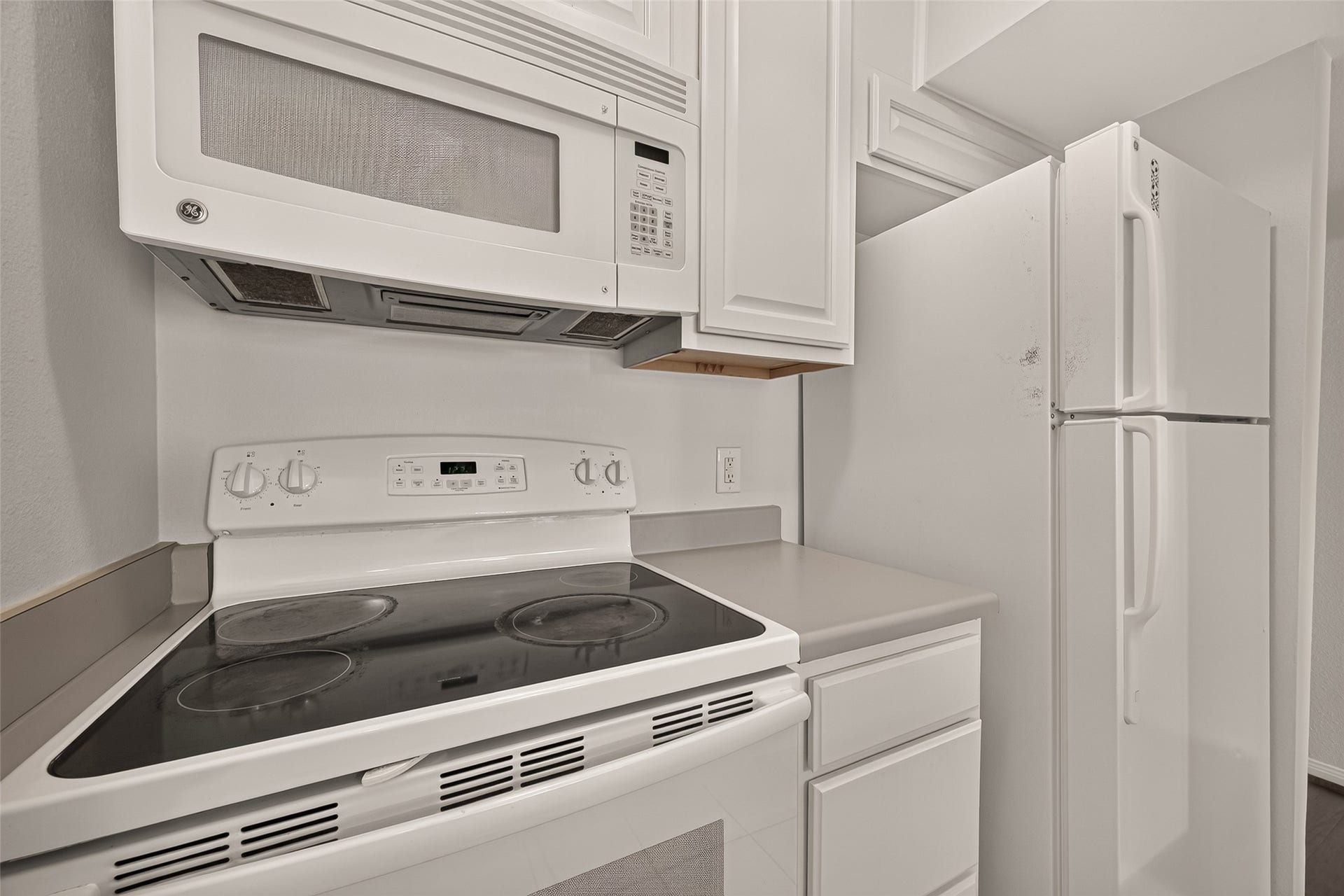 5343 Richmond Avenue, #4, Houston, TX 77056 Modern kitchen equipped with sleek white appliances, including a stove, microwave, and refrigerator, complemented by ample cabinetry for storage.