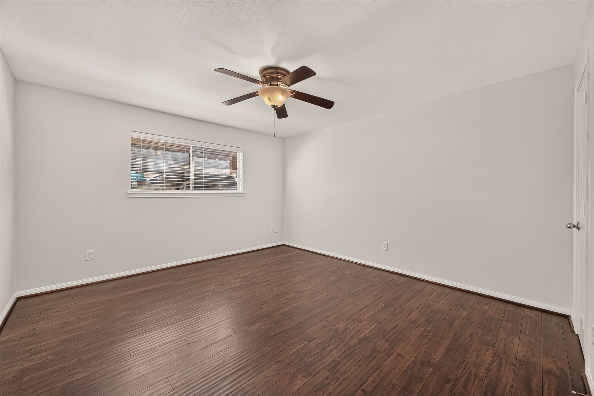 5343 Richmond Avenue, #4, Houston, TX 77056 Spacious and bright room featuring elegant hardwood flooring, a modern ceiling fan, and a large window inviting natural light.