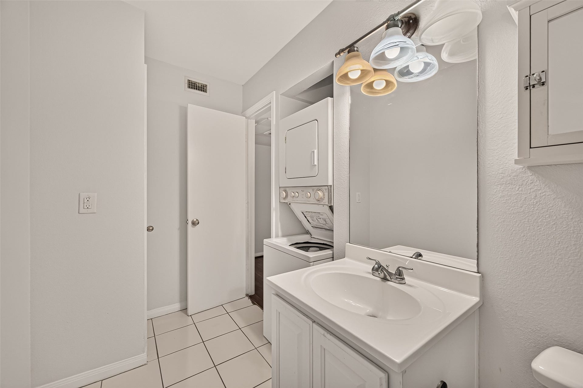 5343 Richmond Avenue, #4, Houston, TX 77056 Bright and functional bathroom featuring a convenient in-unit washer and dryer, sleek vanity with modern lighting, and crisp white tile flooring.
