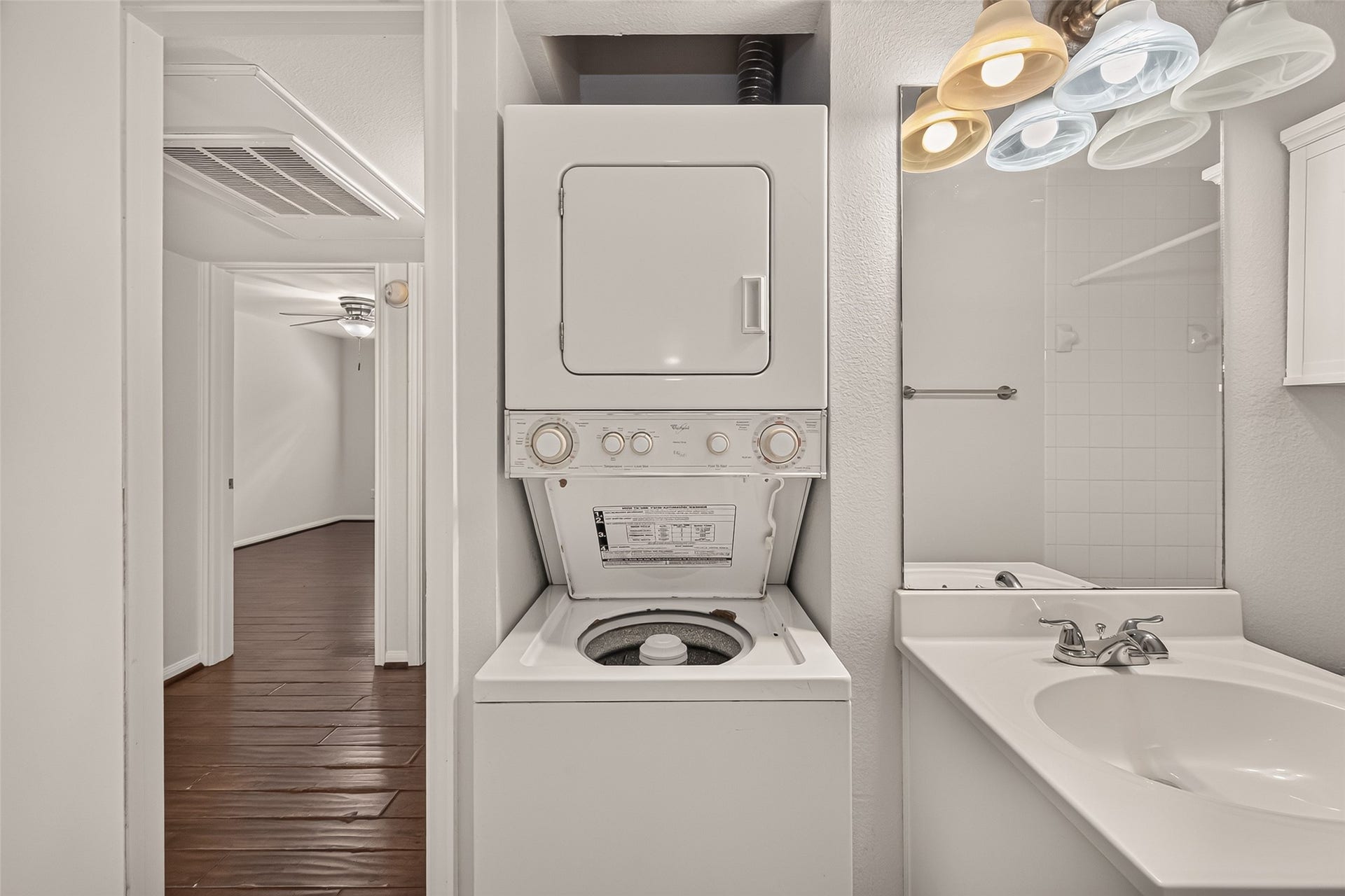 5343 Richmond Avenue, #4, Houston, TX 77056 Convenient in-unit laundry features a stacked washer and dryer adjacent to a sleek bathroom with a modern vanity, all set against rich wood flooring.