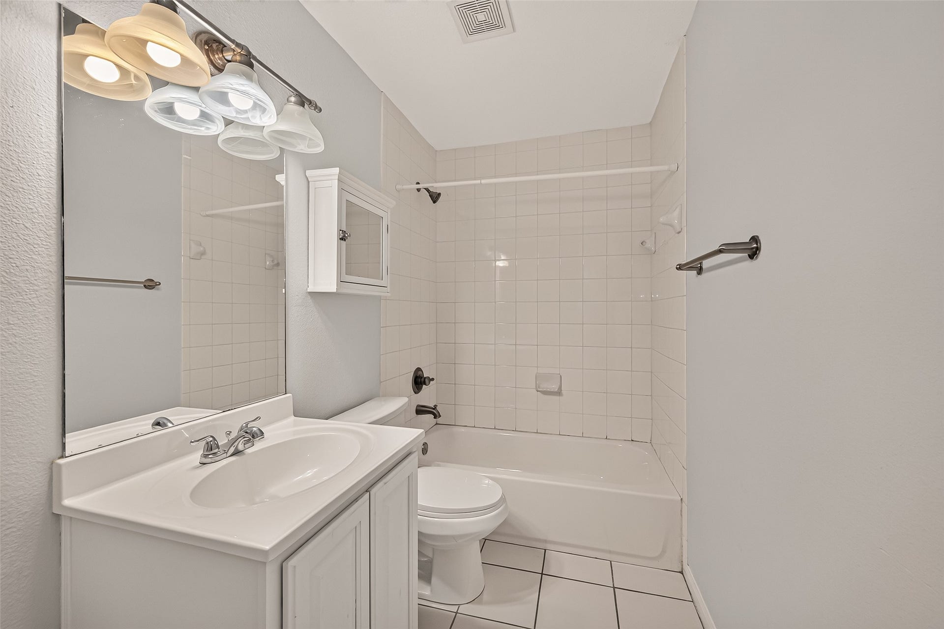 5343 Richmond Avenue, #4, Houston, TX 77056 Modern bathroom with sleek white tiles, a full bathtub, and a stylish vanity, offering a clean and bright space for relaxation.