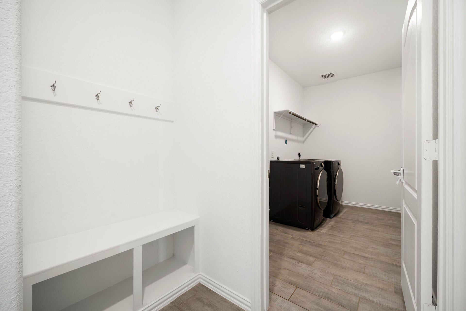 31619 Donoso Drive, Fulshear, TX 77441 A functional mudroom with hooks and built-in bench storage leads into the utility room, complete with washer and dryer connections and a hanging rod for added convenience.
