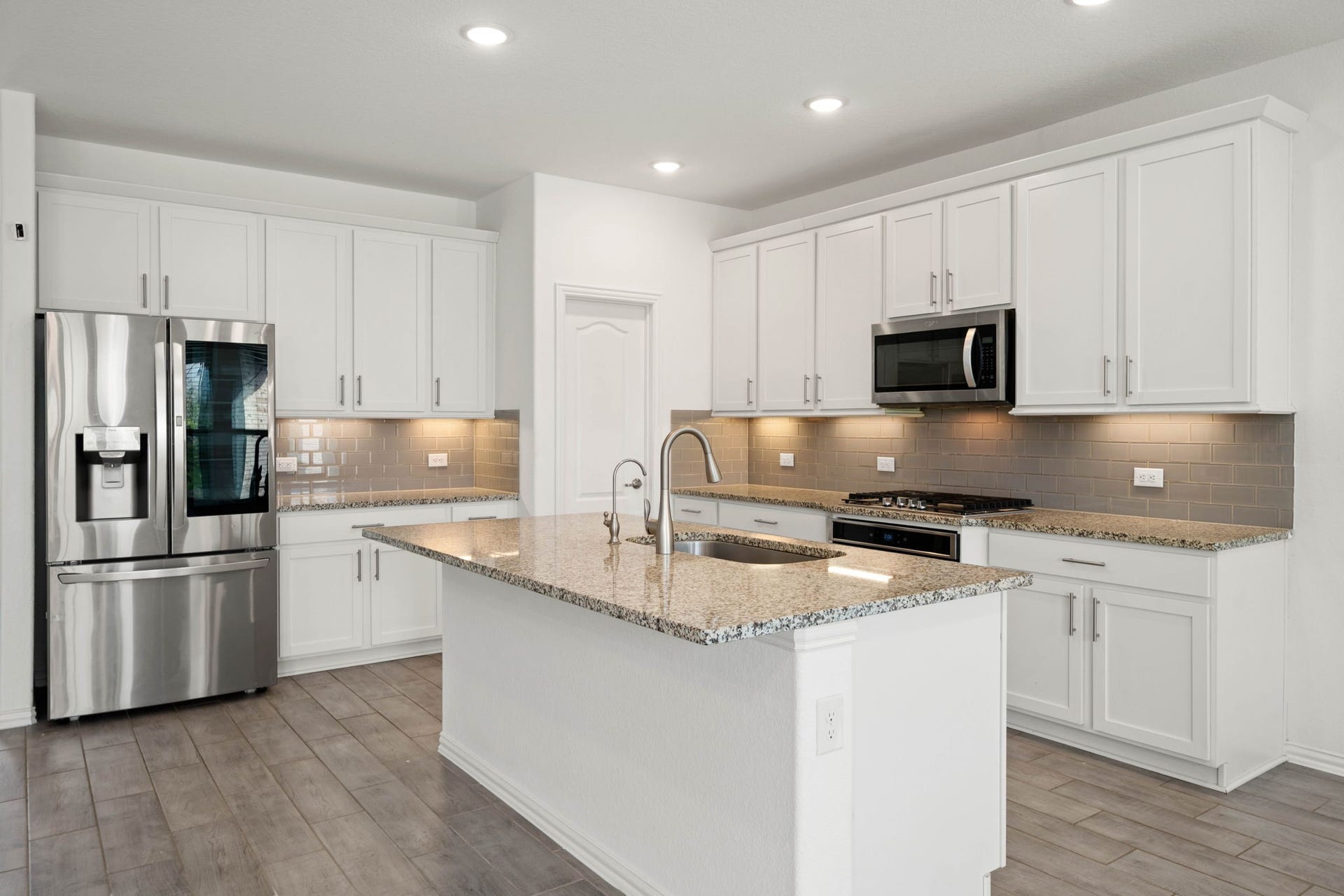 31619 Donoso Drive, Fulshear, TX 77441 The kitchen island offers a granite countertop, undermount sink, and soft-close cabinetry, with a stainless-steel refrigerator completing the space.