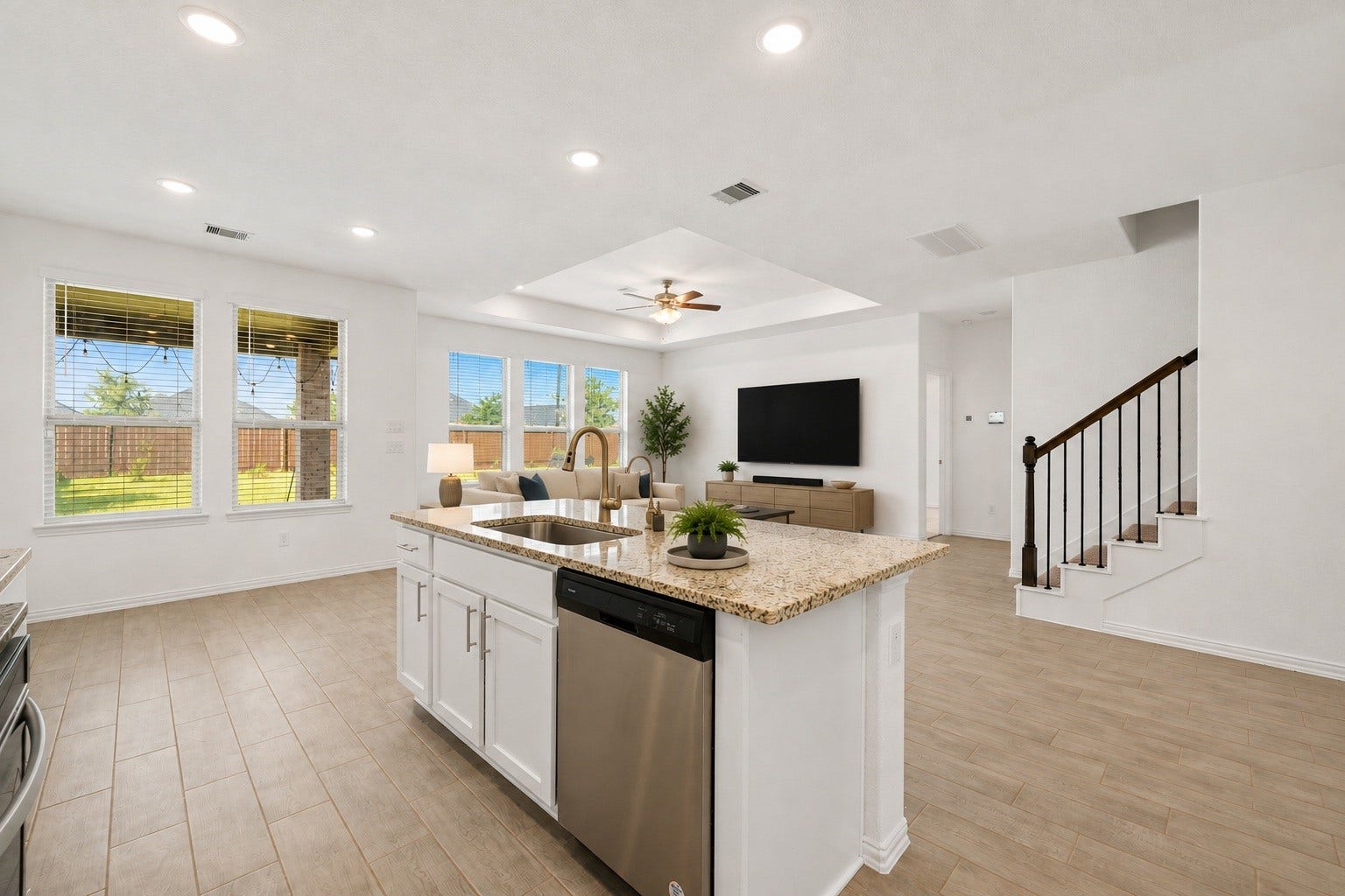 31619 Donoso Drive, Fulshear, TX 77441 Open to the living area, the kitchen island includes a stainless-steel dishwasher, with the staircase to the second floor just beyond. Virtually staged.