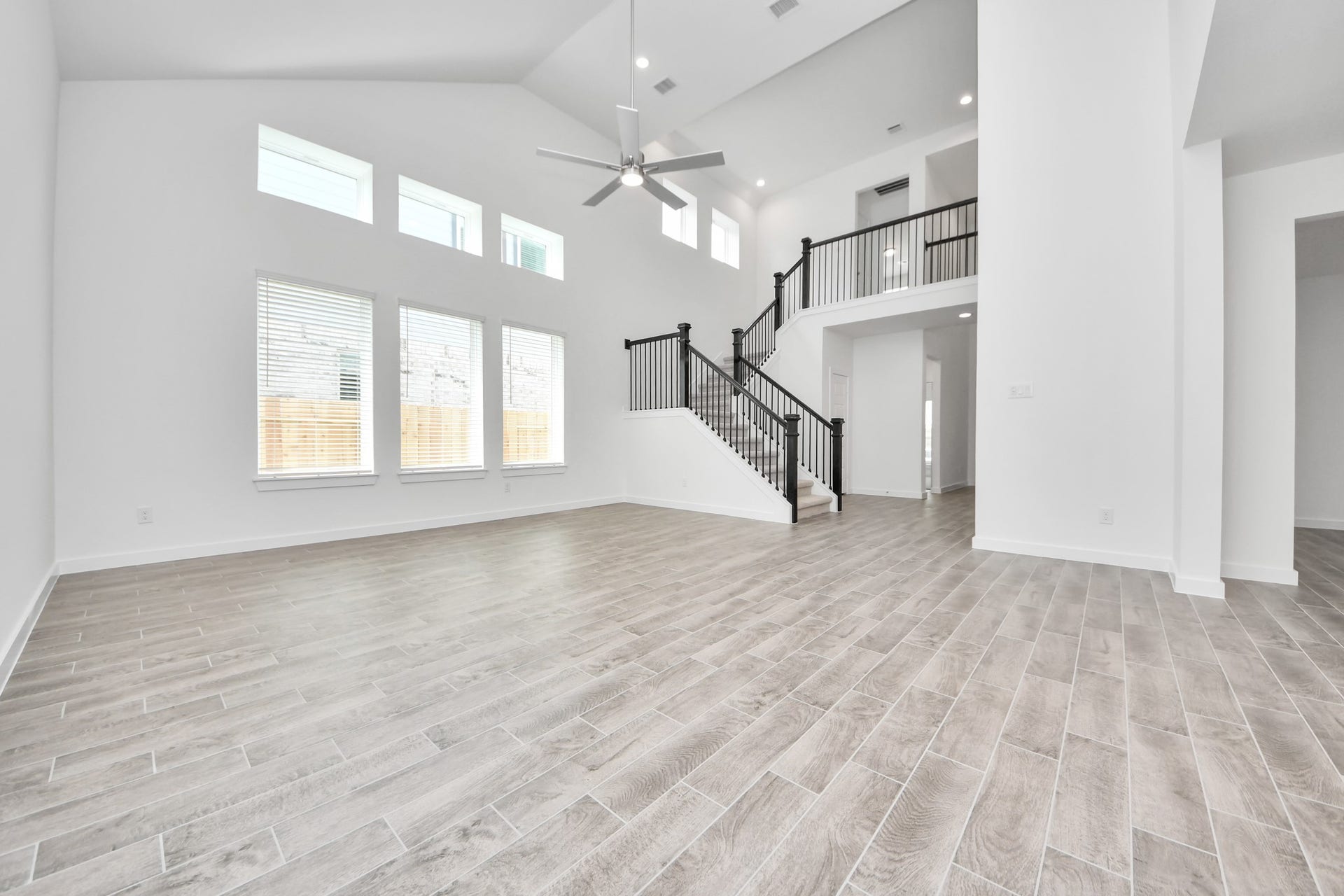 1021 Golden Glow Path, Magnolia, TX 77355 Family room flooded with natural light through the expansive windows. The premium tile flooring adds a touch of luxury to the space, creating the perfect setting for relaxing moments and cherished gatherings with loved ones. Sample photo of completed home with similar floor plan. Actual colors and selections may vary.