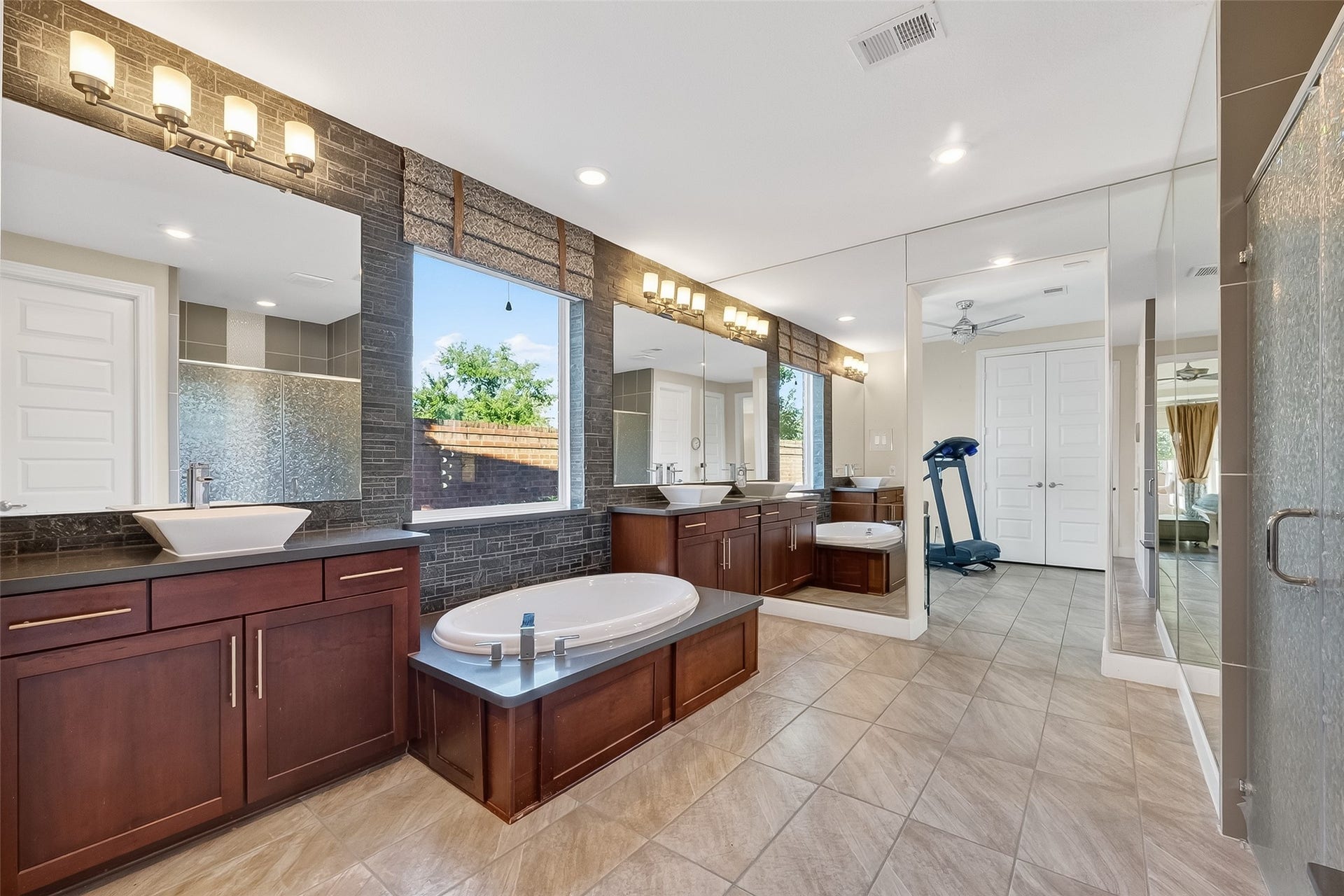 51 Scepter Ridge, Sugar Land, TX 77498 This view of the Primary Bath shows the deep soaking tub flanked by the two separate vanities with vanity mount lavatories. The space beyond the second vanity can be used as an exercise area, a study, an additional closet or anything your heart desires.
