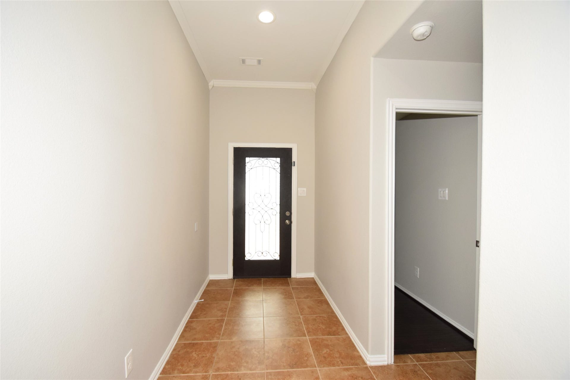 Elegant entry with a glass accent front door, tile floors, crown molding and raised ceilings.