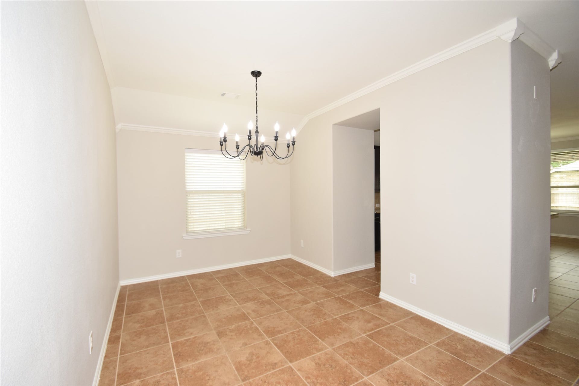 Formal dining room accented by tile floors, raised ceilings, crown molding, and access to the kitchen.