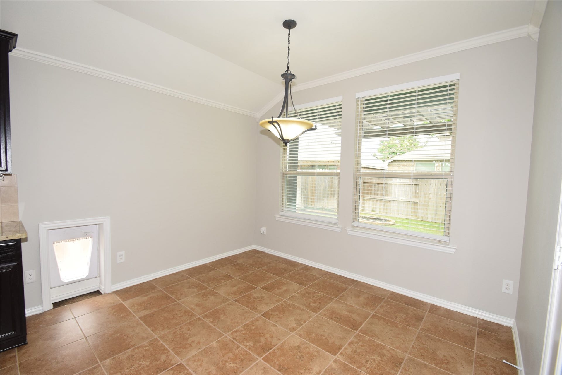 Breakfast room highlighted by tile floors, pet door, crown molding, raised ceilings, open to the kitchen and access to the patio area.