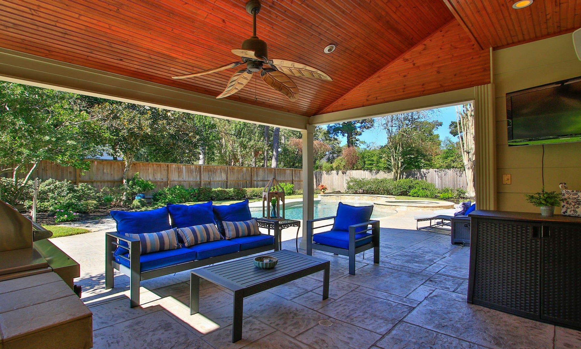 16131 Rudgewick Lane, Spring, TX 77379 Another view of this stunning covered patio featuring elegant seating, a ceiling fan, and views of a sparkling pool surrounded by lush greenery.