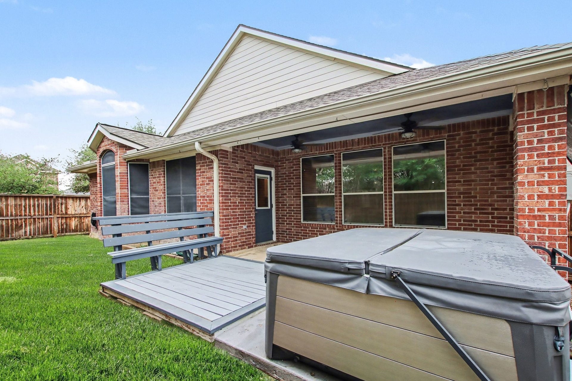 12843 Sherlock Acres Drive, Tomball, TX 77377 Step outside to the backyard with a massive covered patio, dual fans, an extended deck with bench seating, and a hot tub.