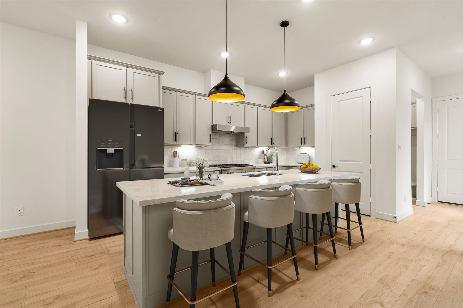 5018 Schuler Street, Houston, TX 77007 Sleek culinary hub quartz waterfall island with comfortable counter stool seating, statement drop lighting, integrated stainless appliances, and wide-plank wood-look flooring.