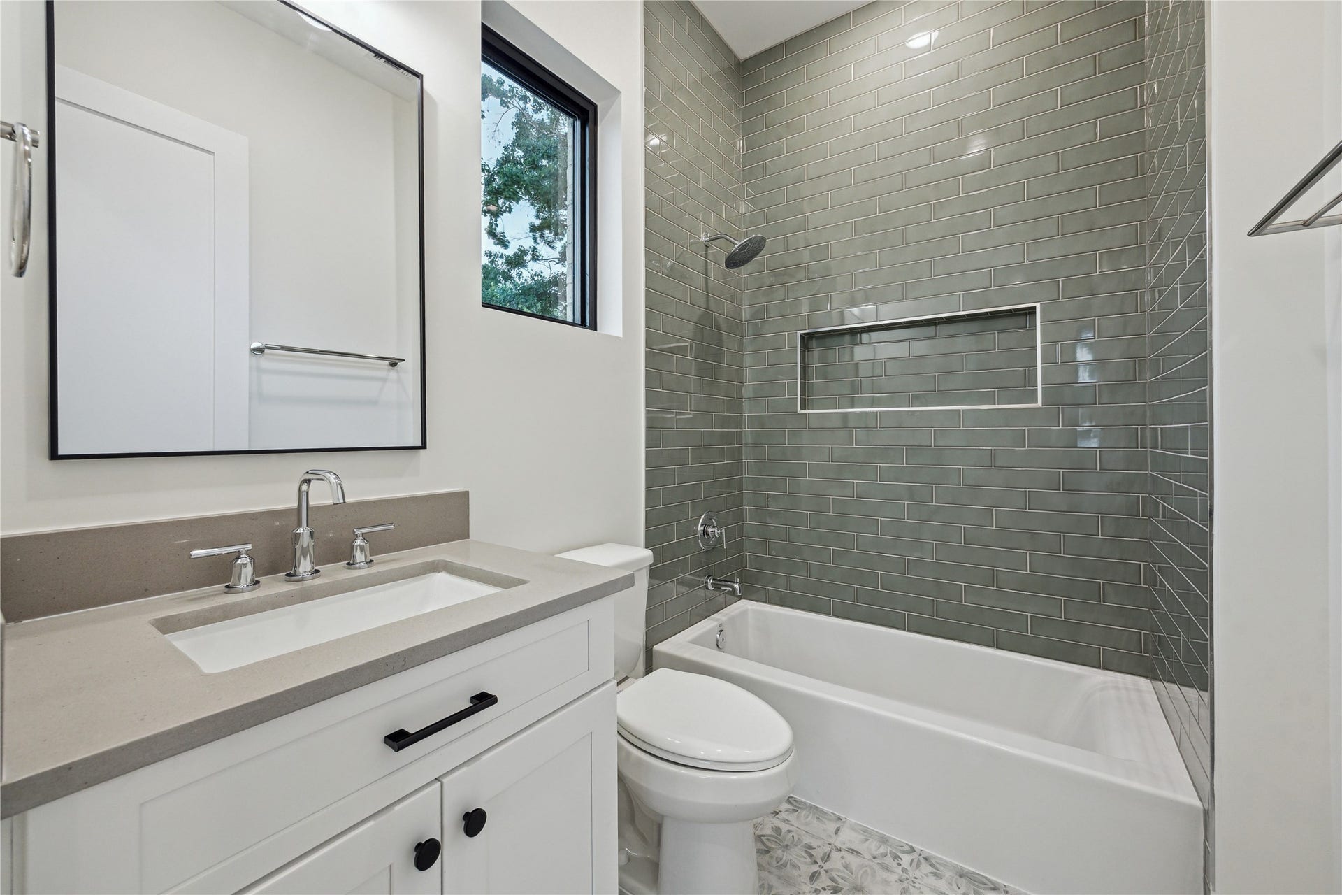 431 W 30th Street, Houston, TX 77018 Modern bathroom featuring a sleek vanity with dual faucets, a large mirror, and a window for natural light. The bathtub is surrounded by stylish subway tiles, and there's a convenient built-in shelf.